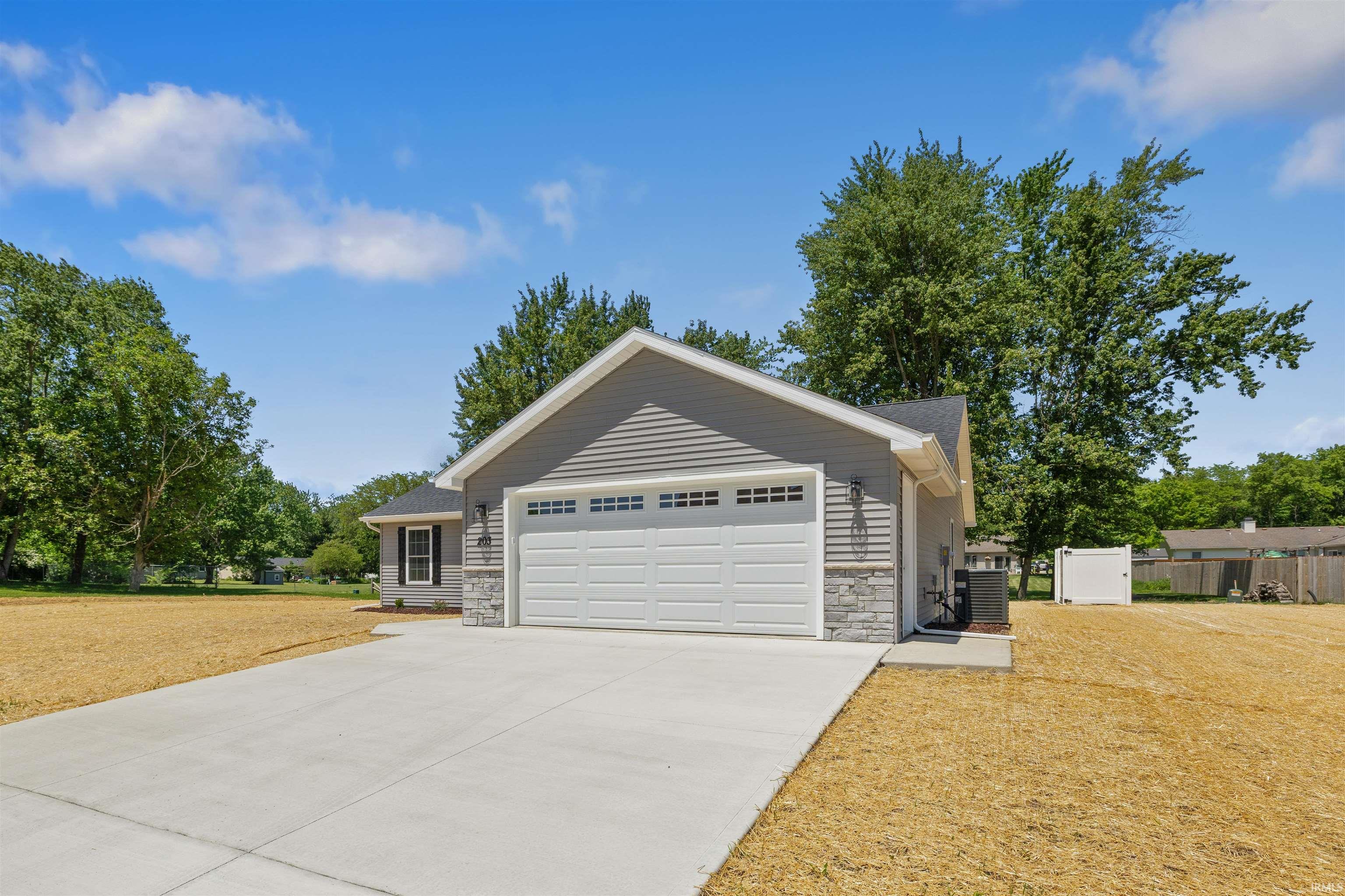 New construction home featuring gray horizontal siding, stone veneer accents, and a white two-car garage door