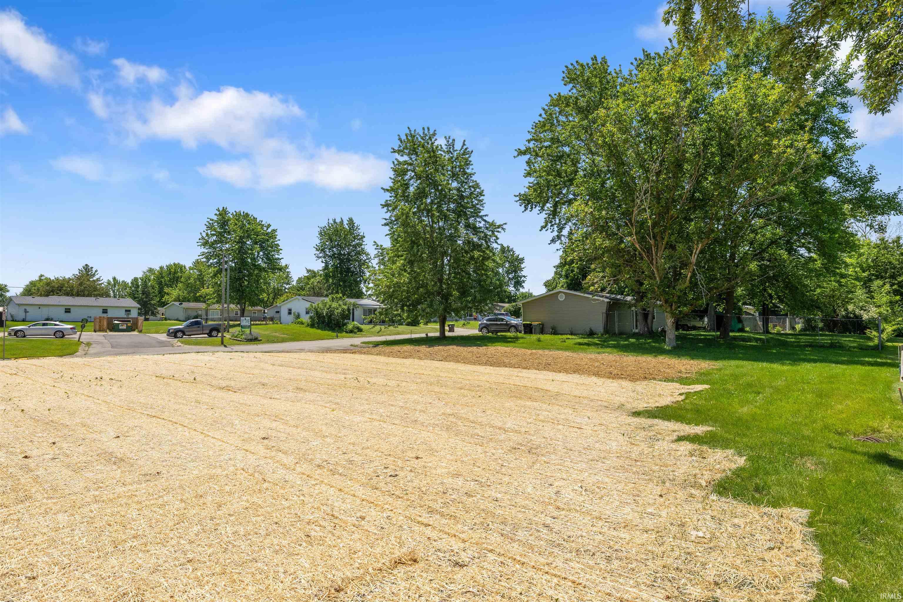 Spacious cleared lot with partially mulched ground and an established green lawn border