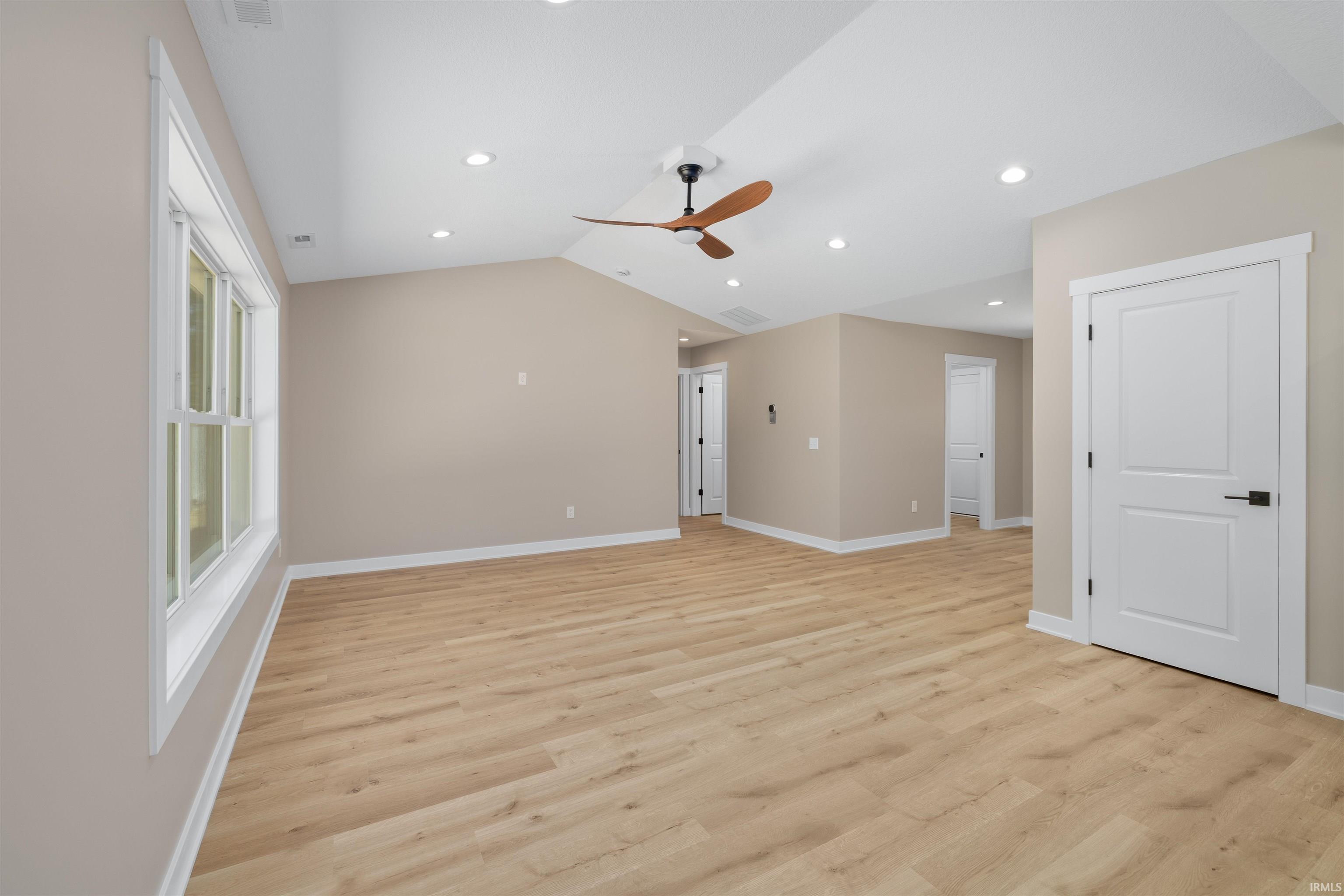 Spacious room featuring wood-finish flooring, vaulted ceiling, and recessed lighting