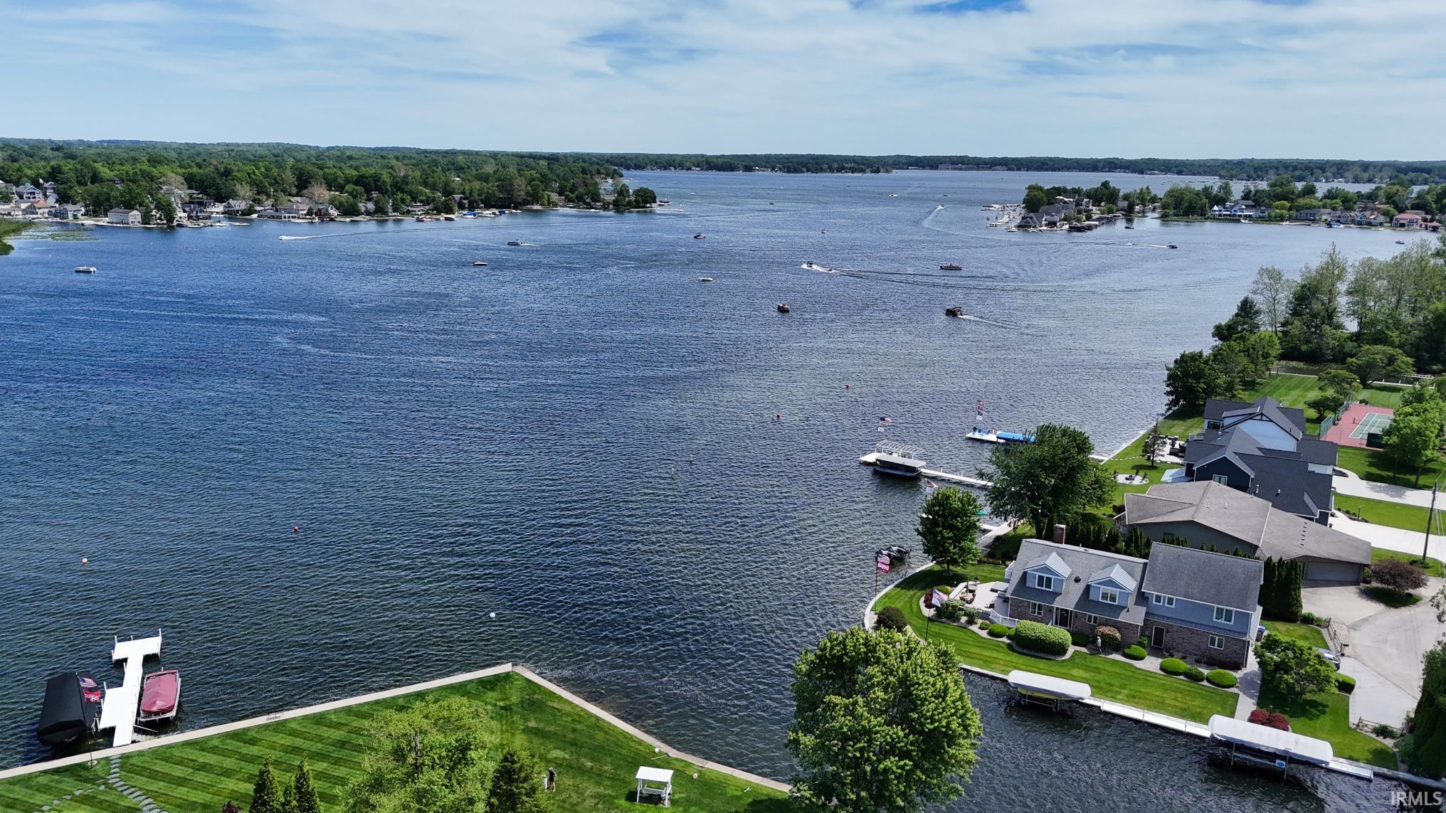Expansive waterfront property featuring a private dock, manicured lawn, and mature trees