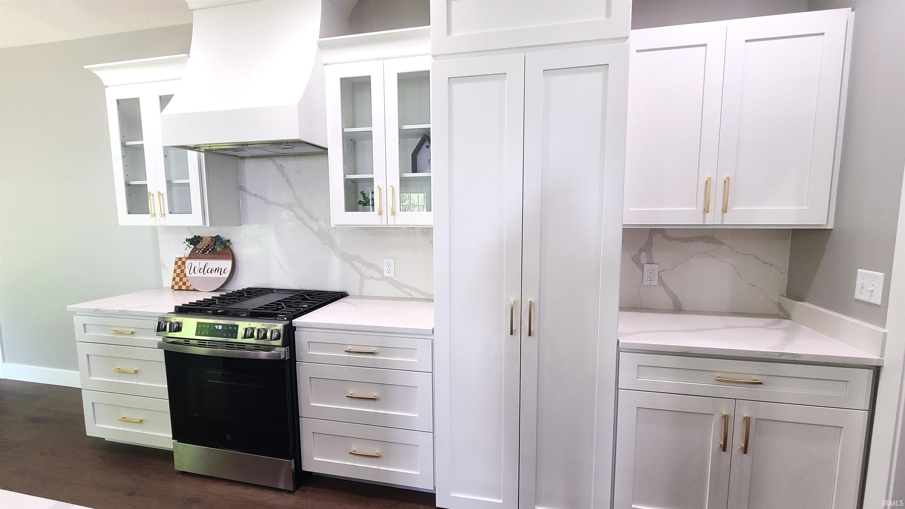 Modern kitchen featuring a gas range, white cabinetry with gold-tone hardware, and light countertops