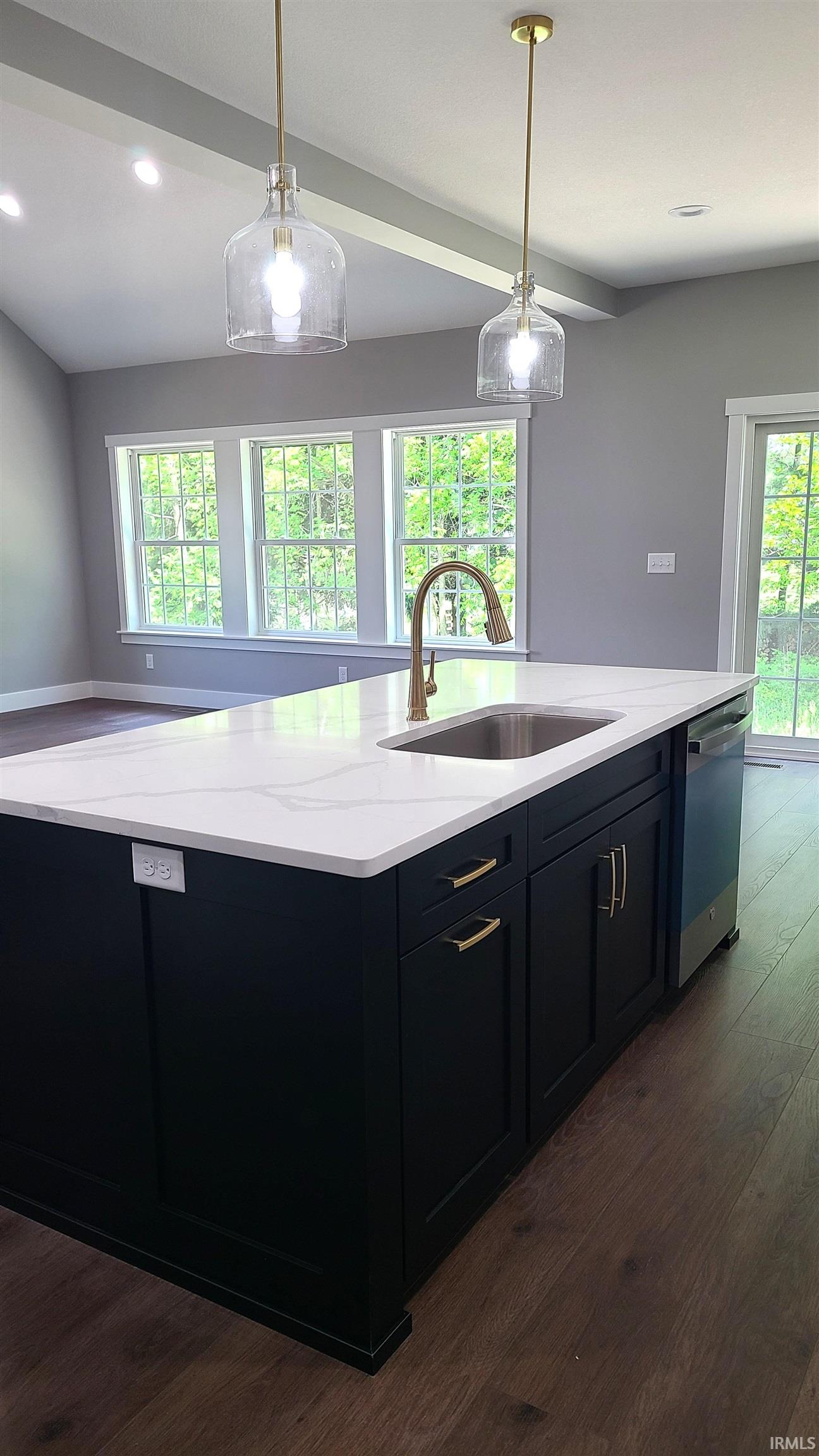 Kitchen island featuring a stainless steel sink, gold-finish faucet, and white countertop