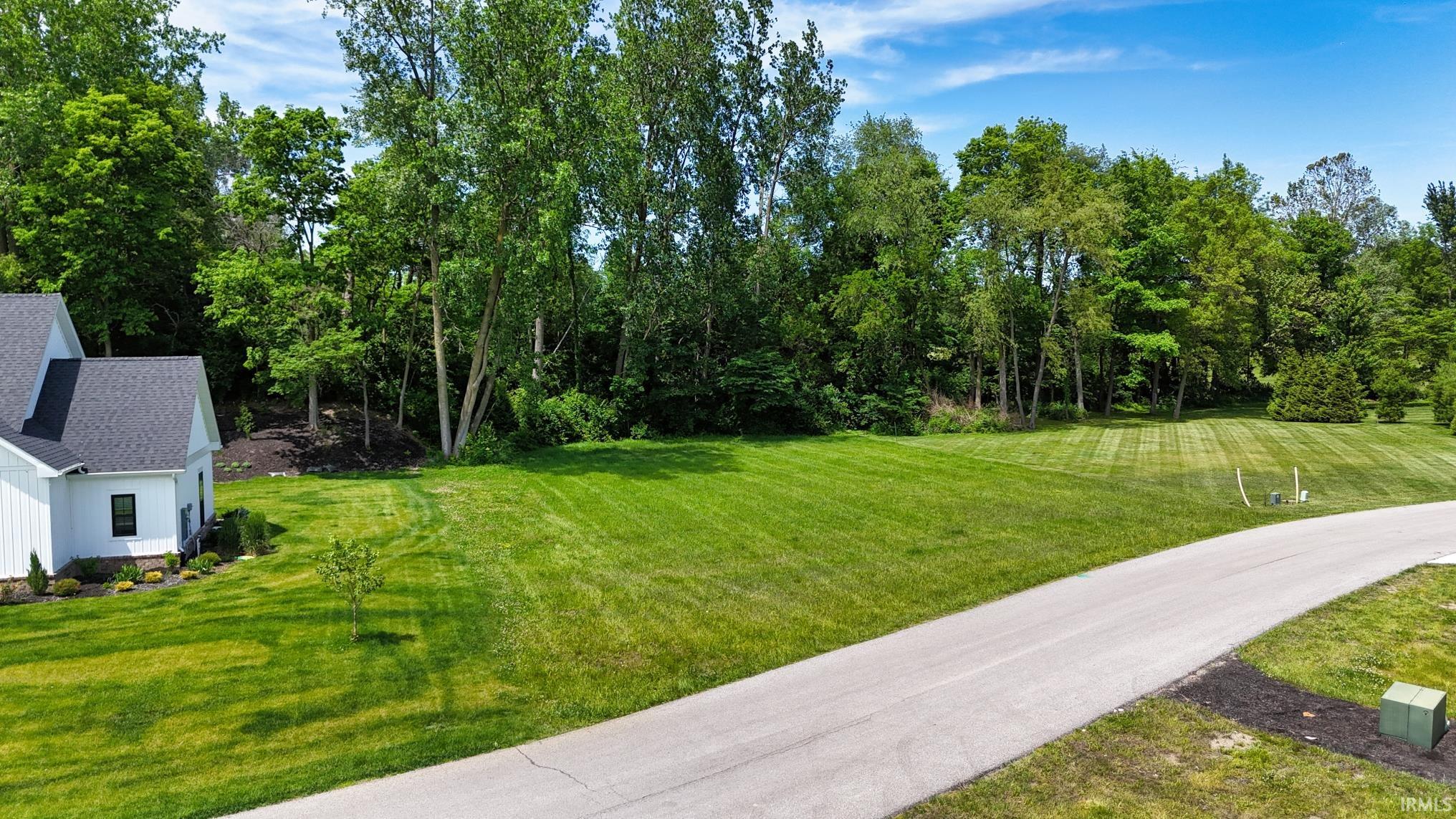 Expansive open lot featuring a manicured lawn and mature tree line