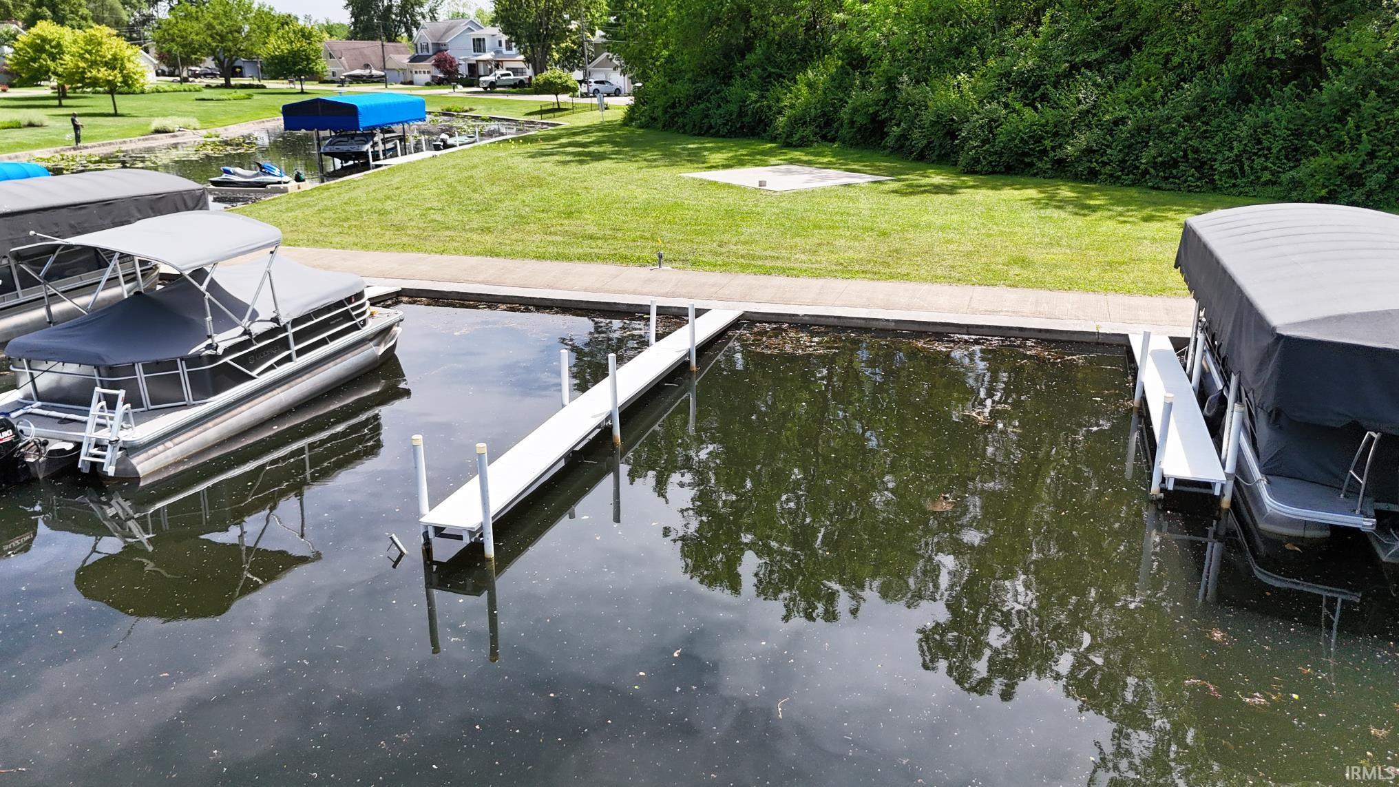 Waterfront property featuring multiple boat slips, a fixed dock, a floating dock, and manicured grassy areas