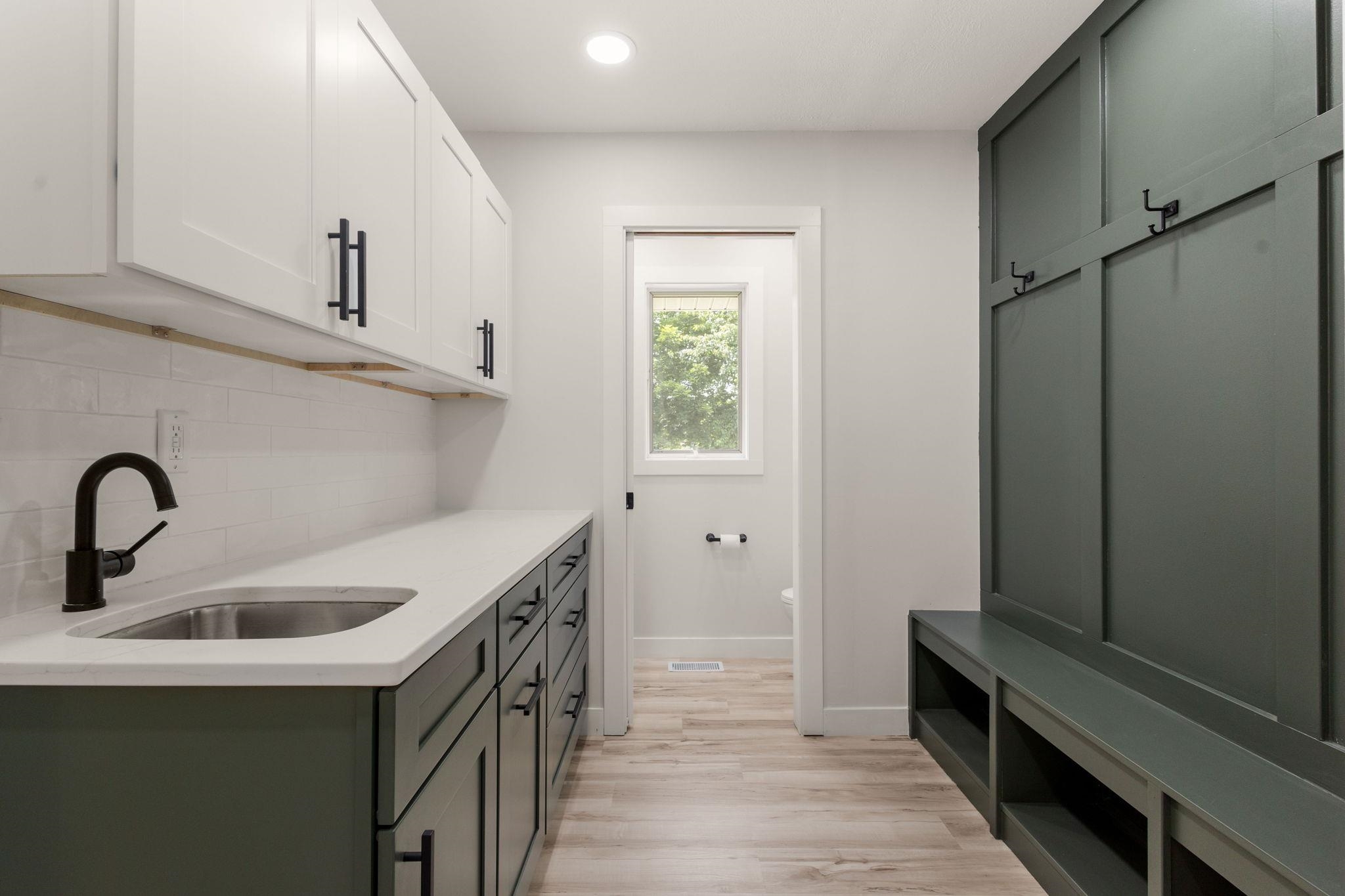 Mudroom featuring a built-in bench with storage, floor-to-ceiling cabinetry, and light wood-finish flooring