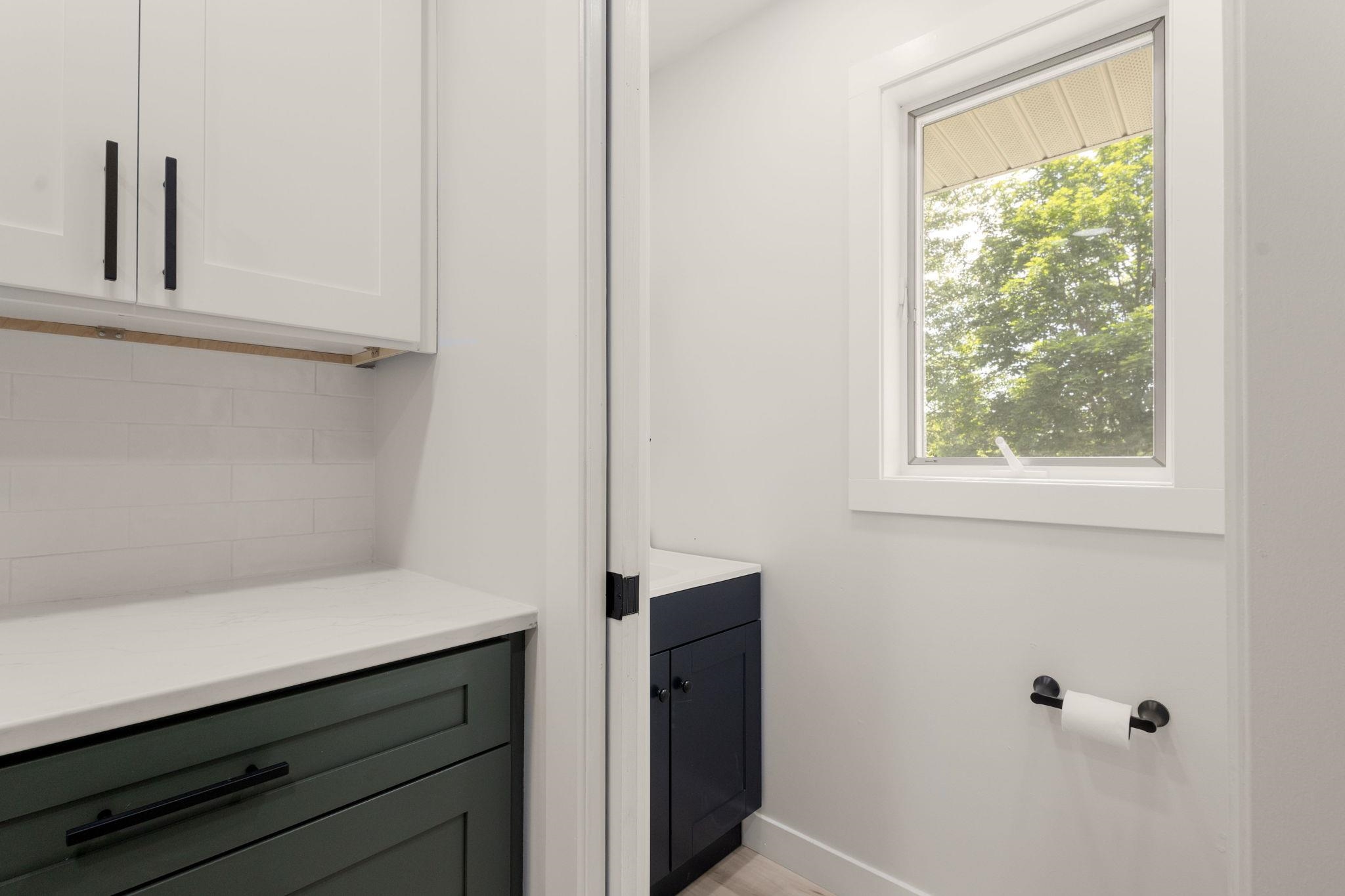 White upper cabinetry with contrasting lower green cabinetry featuring black hardware