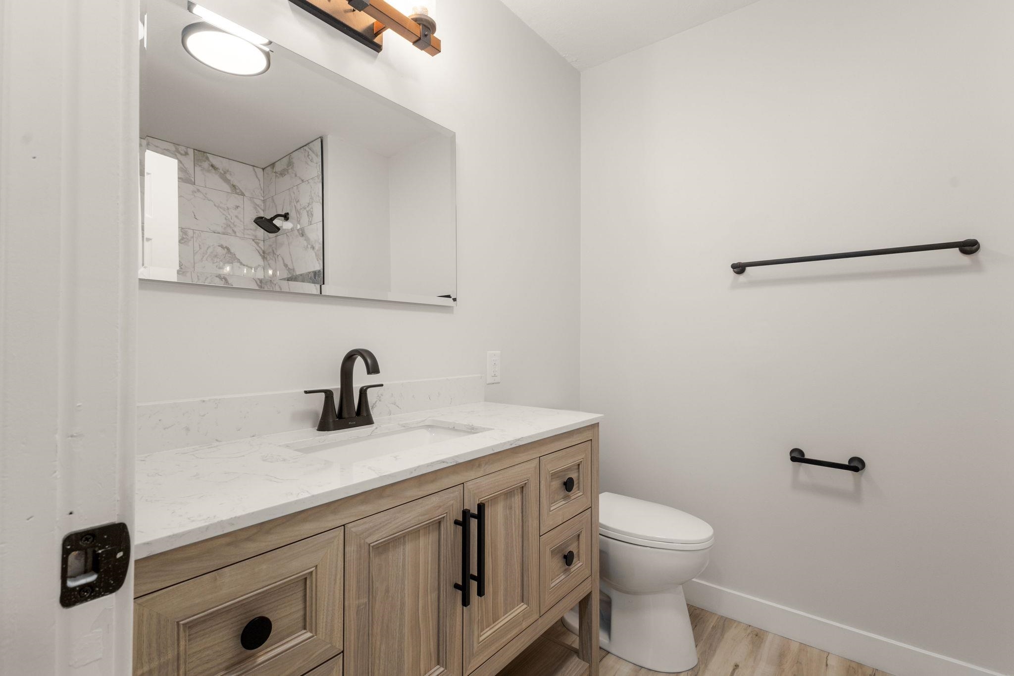 Bathroom featuring a light wood-finish vanity with a white countertop and matte black hardware