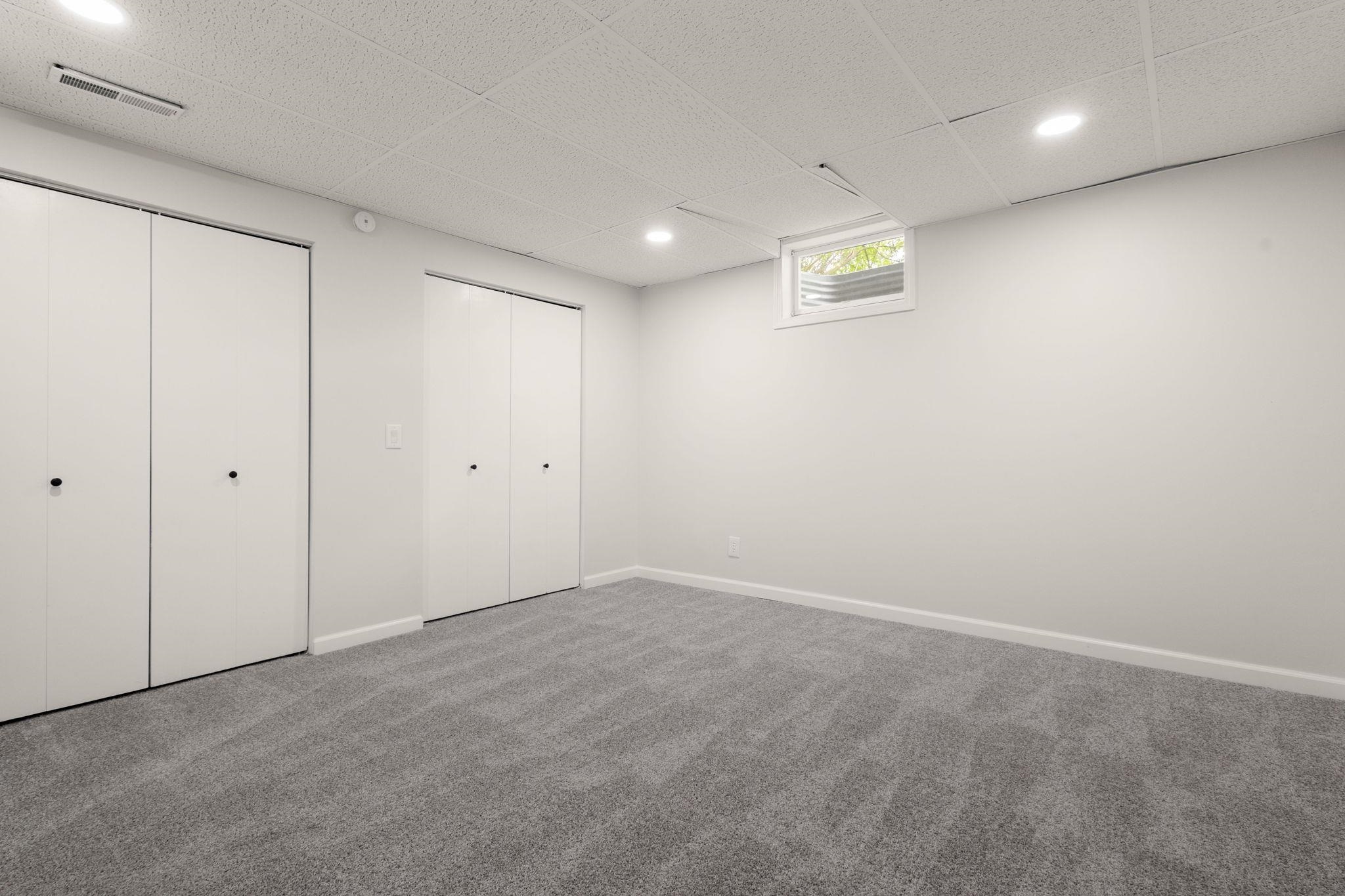 Carpeted room featuring two bifold door closets, recessed lighting, and a white-trimmed window