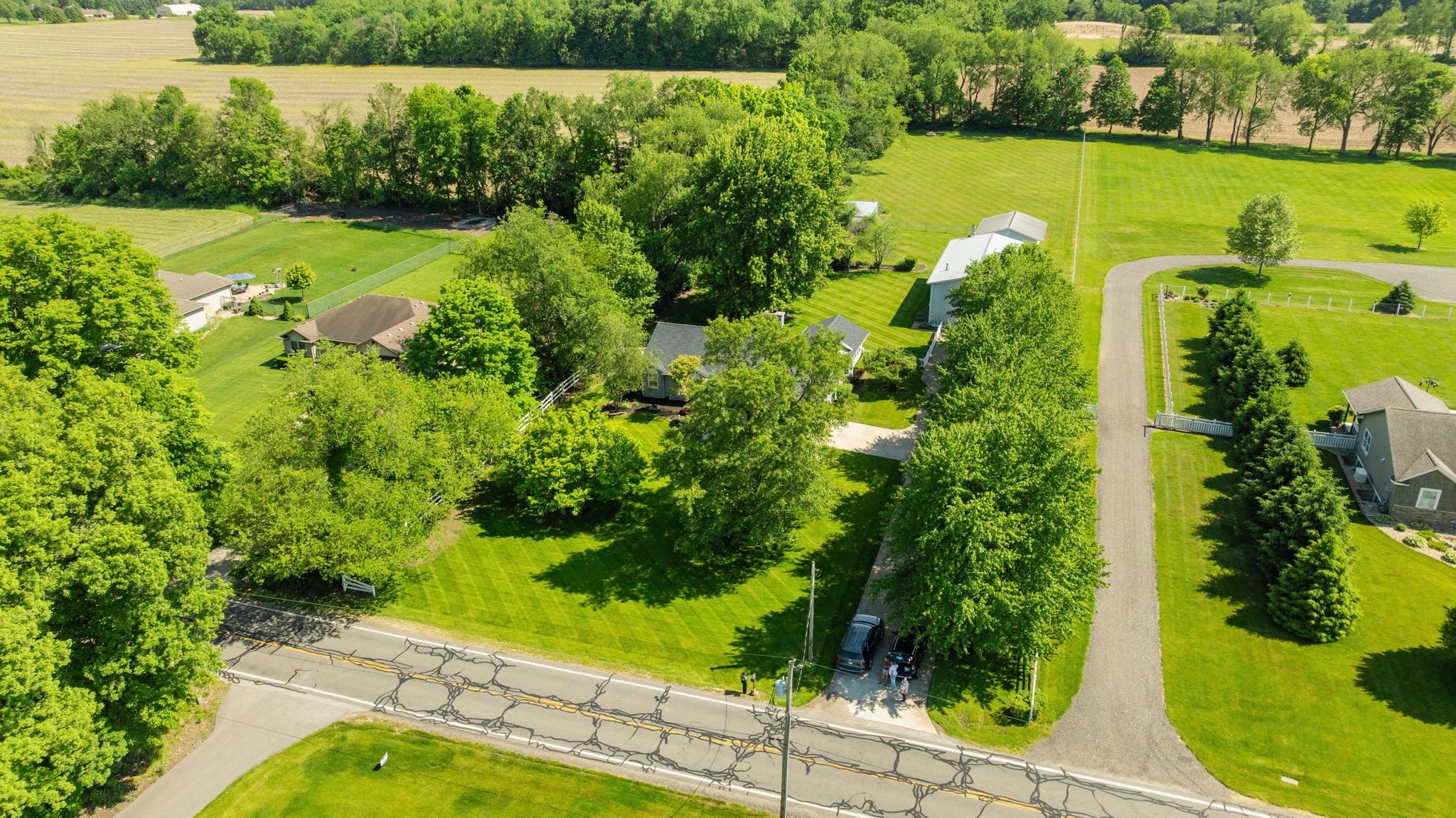 Expansive property featuring a paved driveway, mature trees, and a substantial grassy area