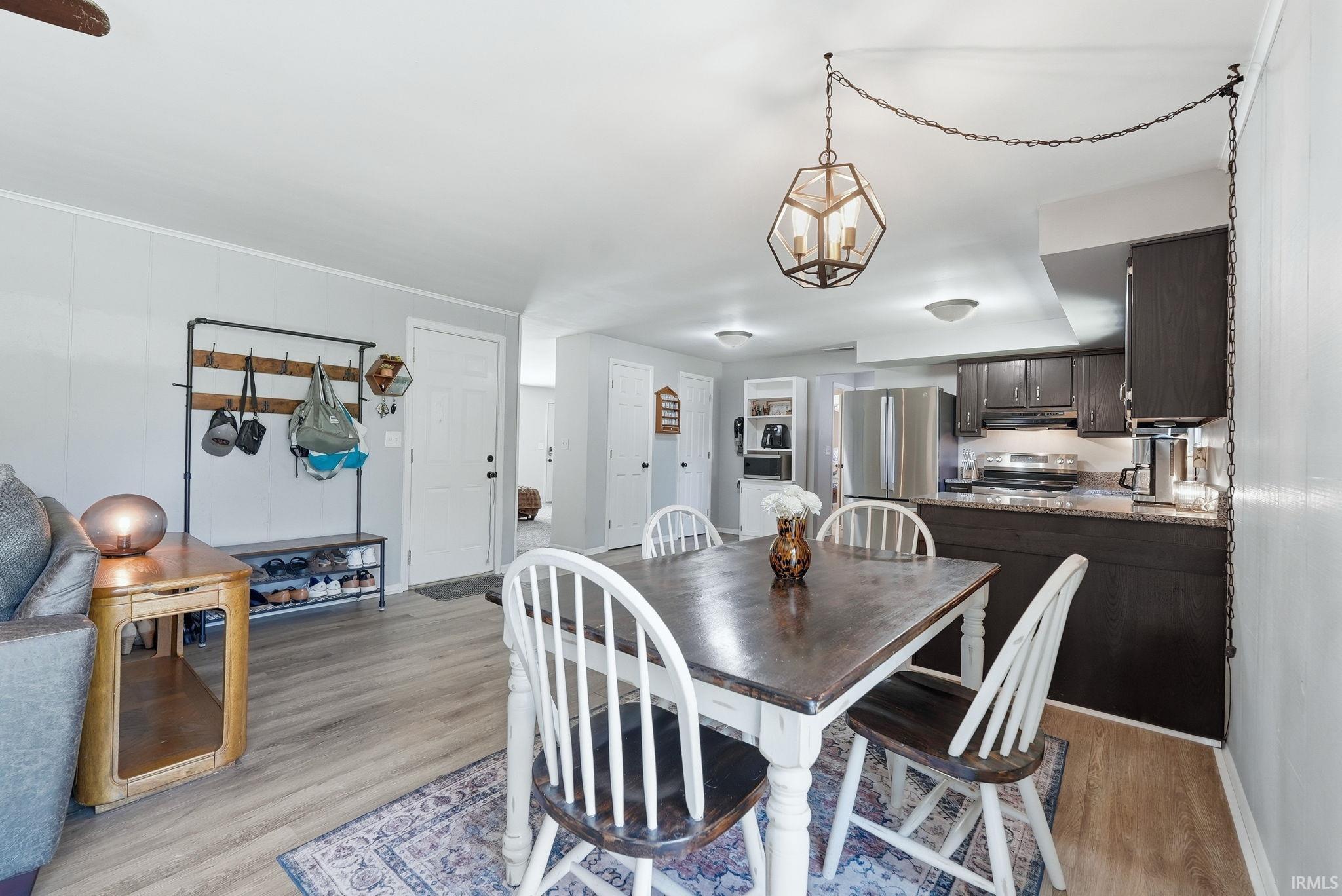 Dining area with modern hexagonal pendant light fixture, wood-finish flooring, and light gray wall paneling