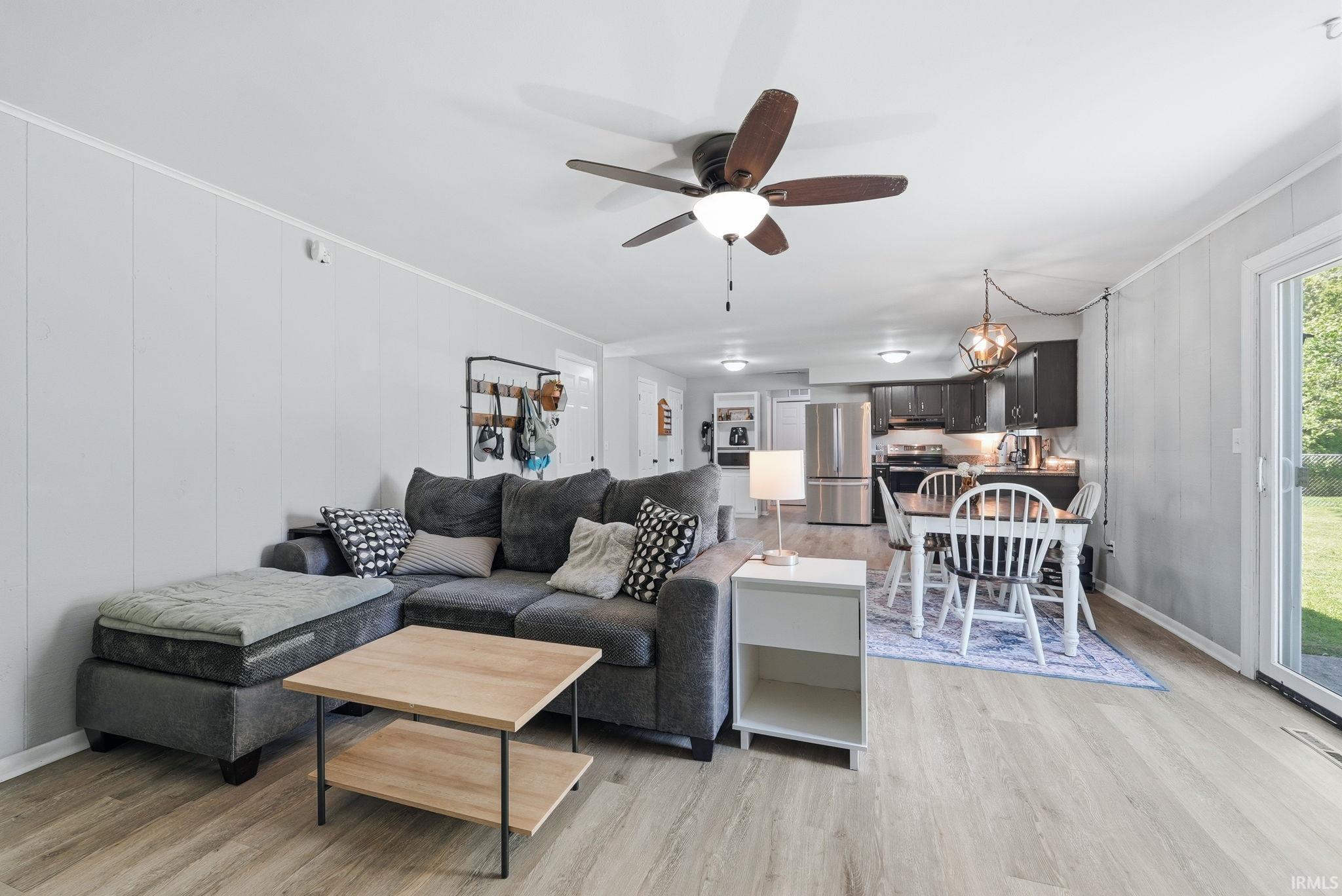 Open-concept living area featuring wood-finish flooring, a ceiling fan, and board and batten style walls