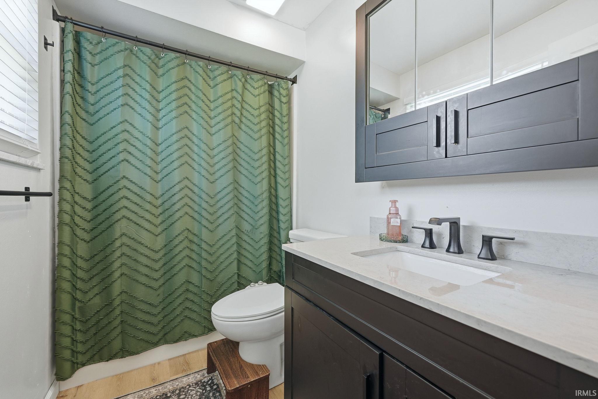 Bathroom featuring a dark wood-finish vanity with a light countertop, an undermount sink, and a matte black faucet