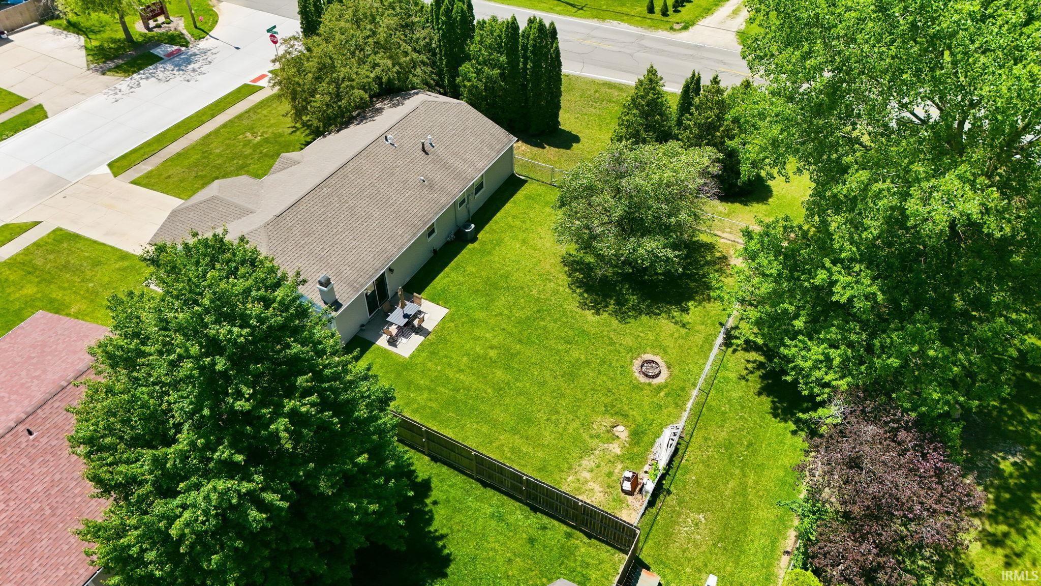 Expansive green lawn with mature trees, fenced perimeter, and dedicated patio area