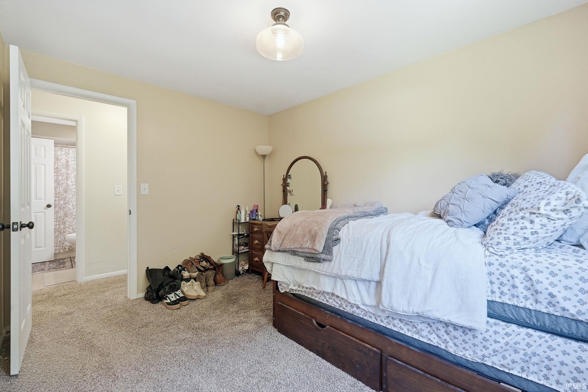 Carpeted bedroom featuring a clear passageway, a flush-mount ceiling light fixture, and neutral wall tones