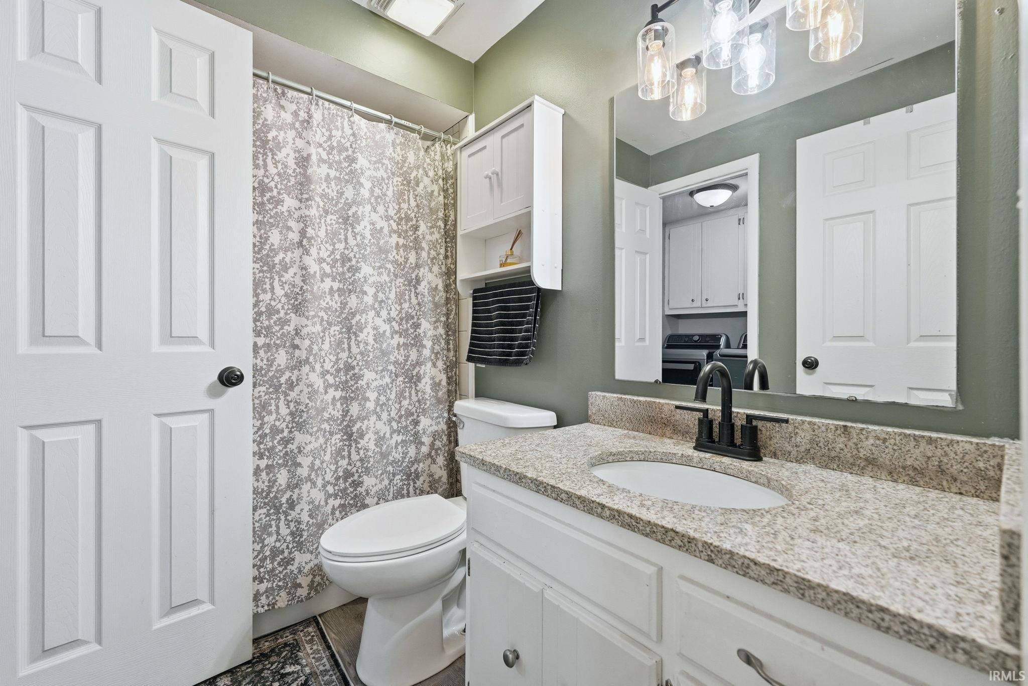 Bathroom vanity with granite-style countertop, undermount sink, and matte black faucet