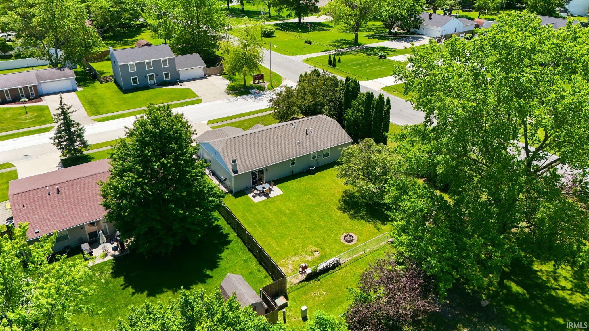 Spacious backyard featuring a manicured lawn, established trees, privacy fencing, and a patio area