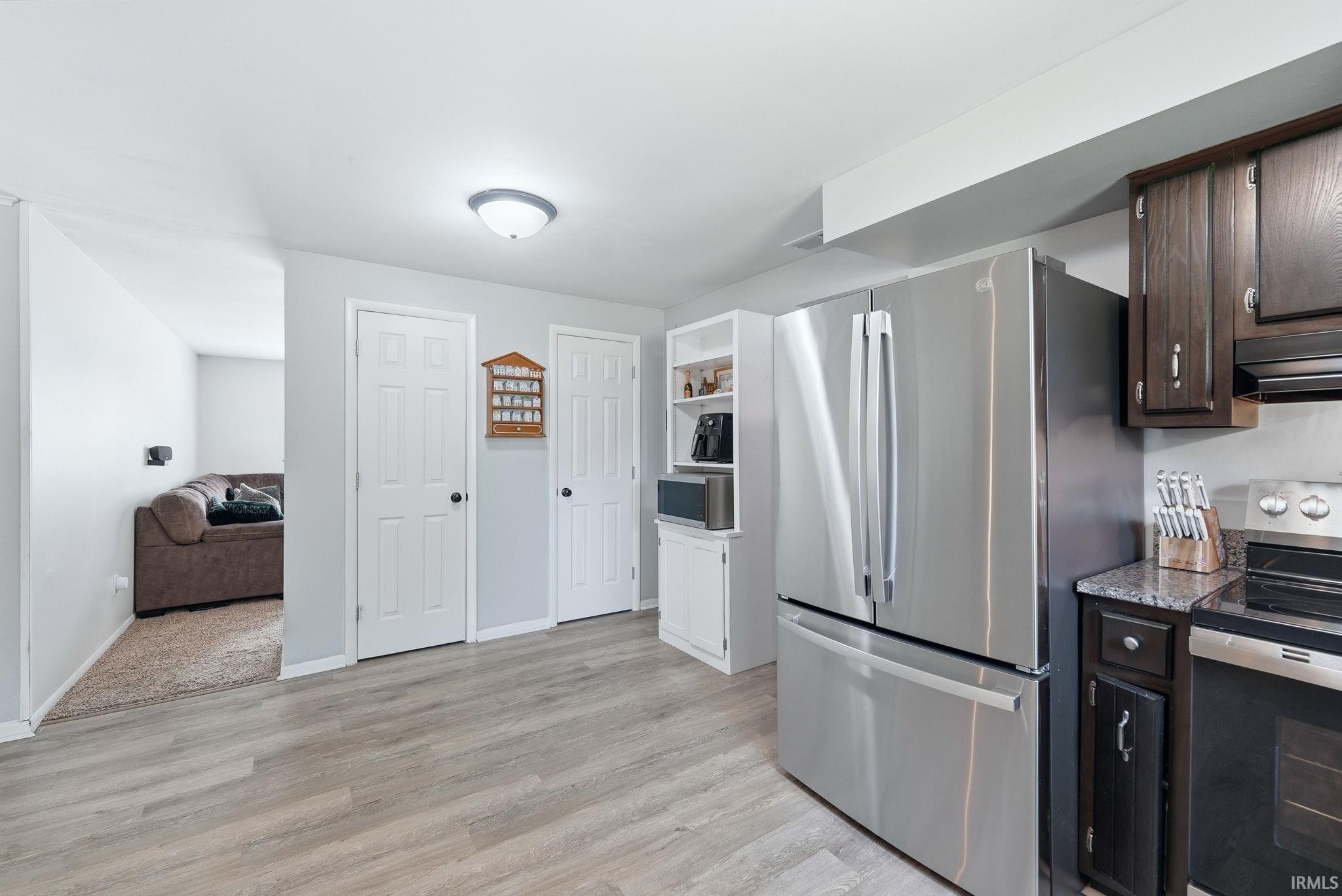 Kitchen space featuring stainless steel appliances, dark wood cabinetry, and granite-style countertops