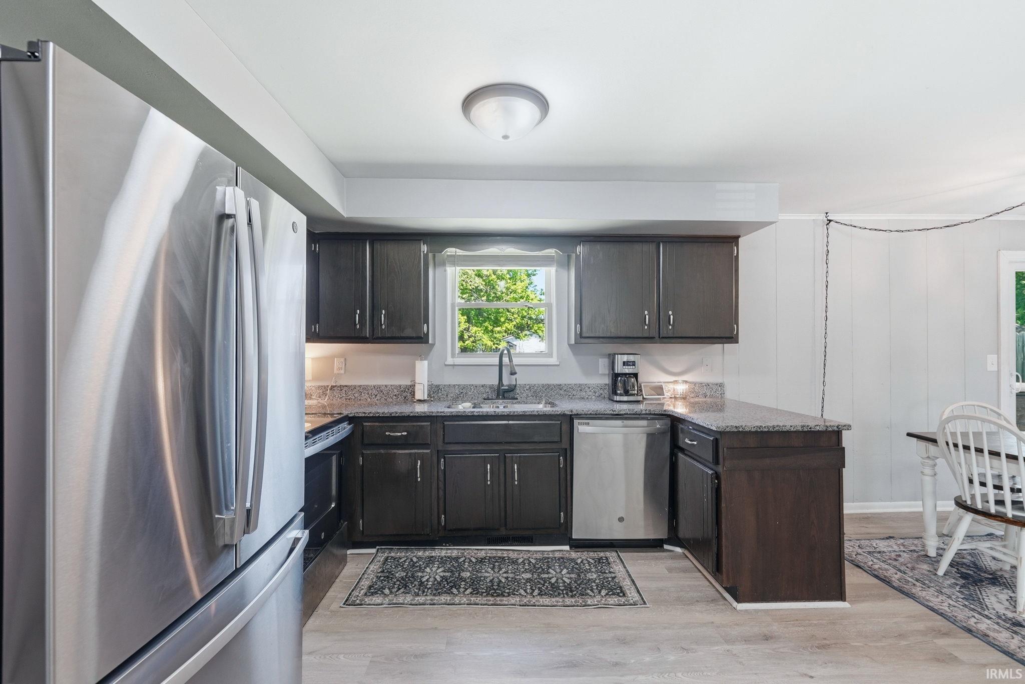 Kitchen featuring dark wood cabinetry, light-toned countertops, and stainless steel appliances