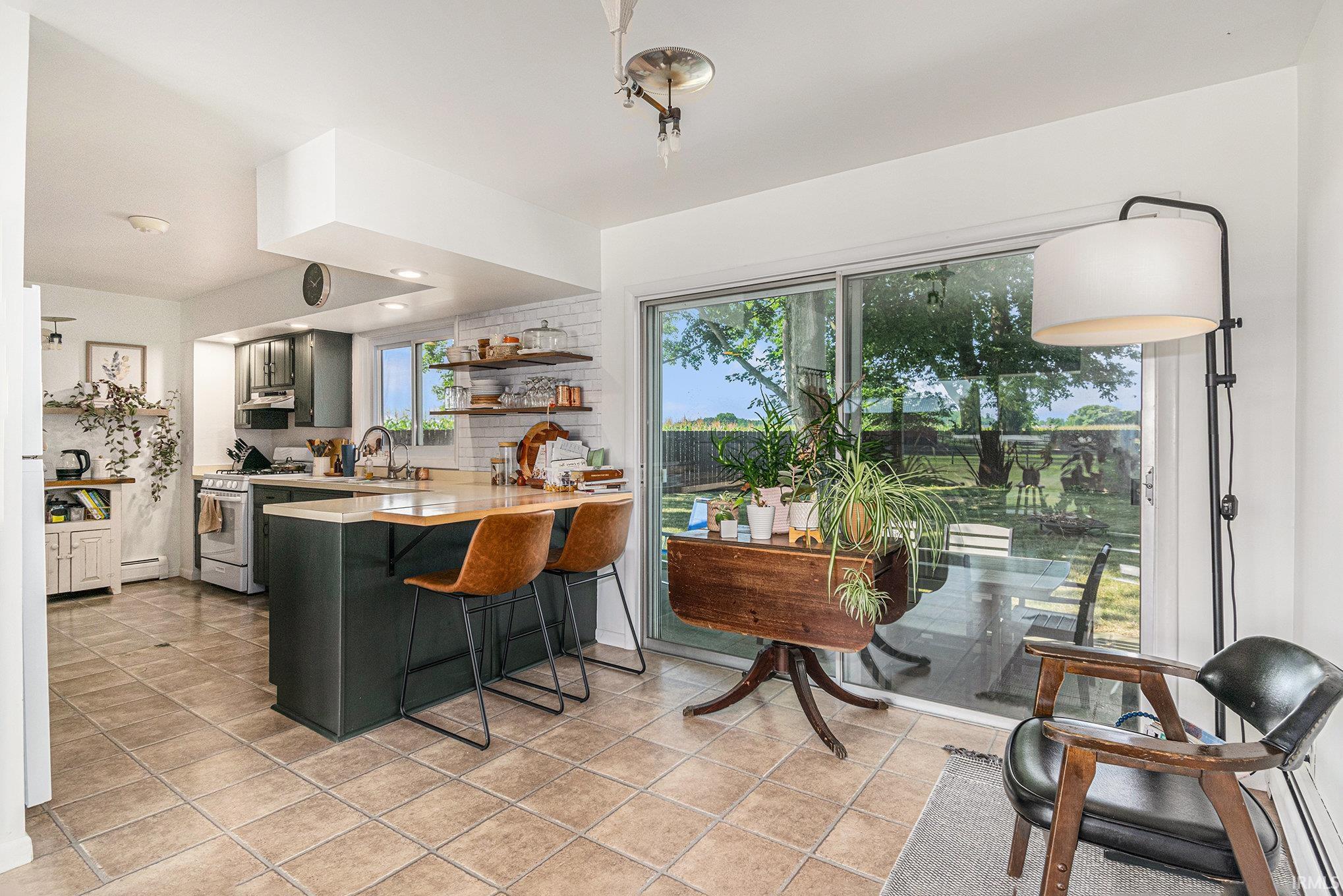 Kitchen featuring dark cabinetry, light countertops, a white subway tile backsplash, and open shelving