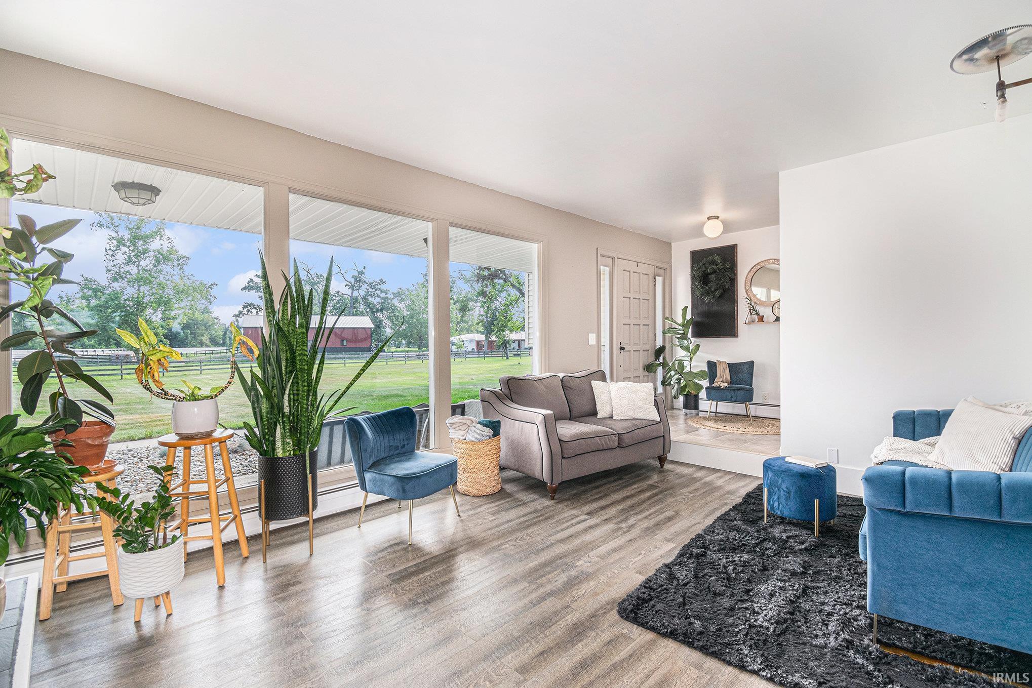 Expansive windows showcasing a green landscape, wood-finish flooring, recessed lighting, and a defined entry area