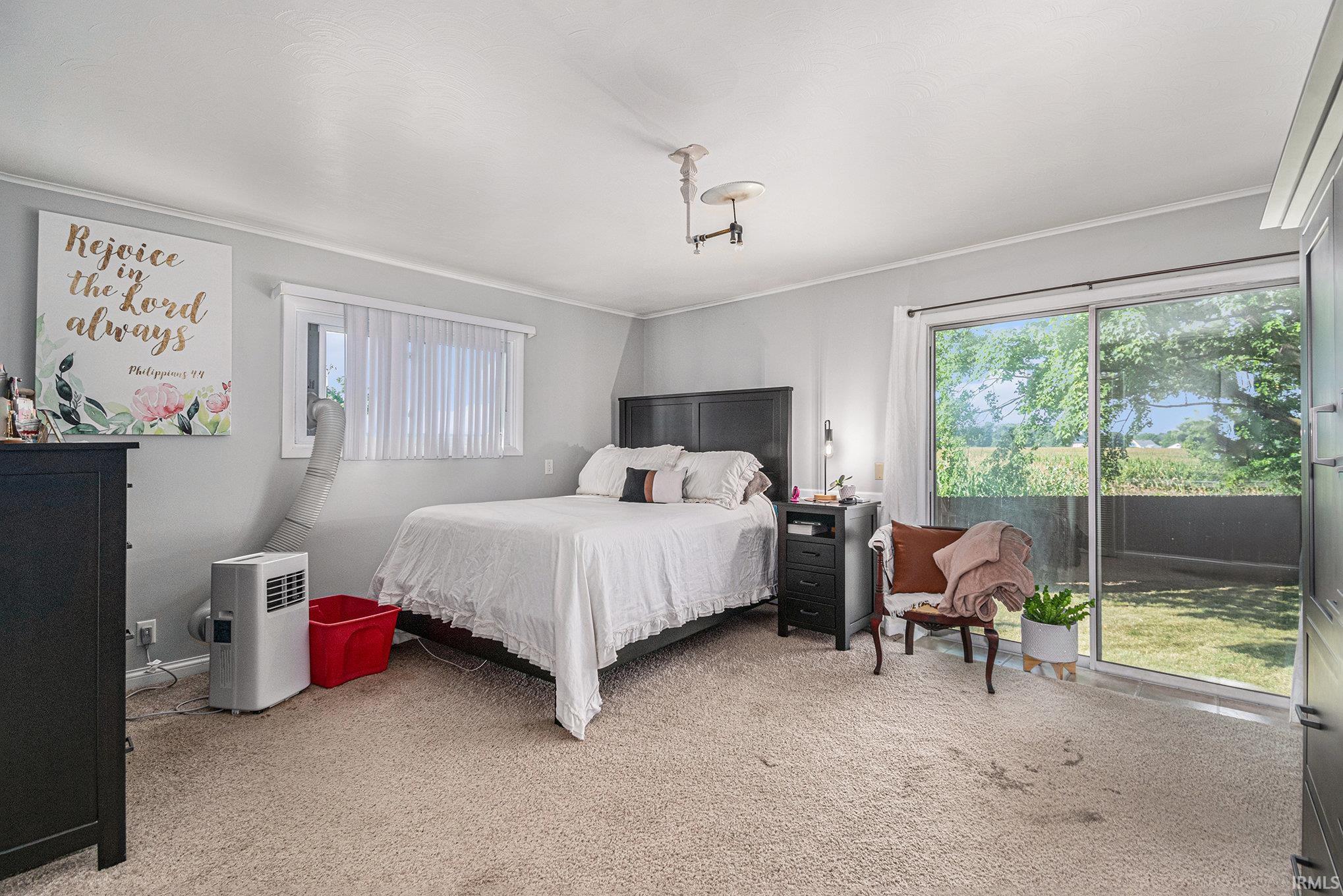 Sliding glass door opening to outdoor space, dark wood-finish headboard, and bedside table