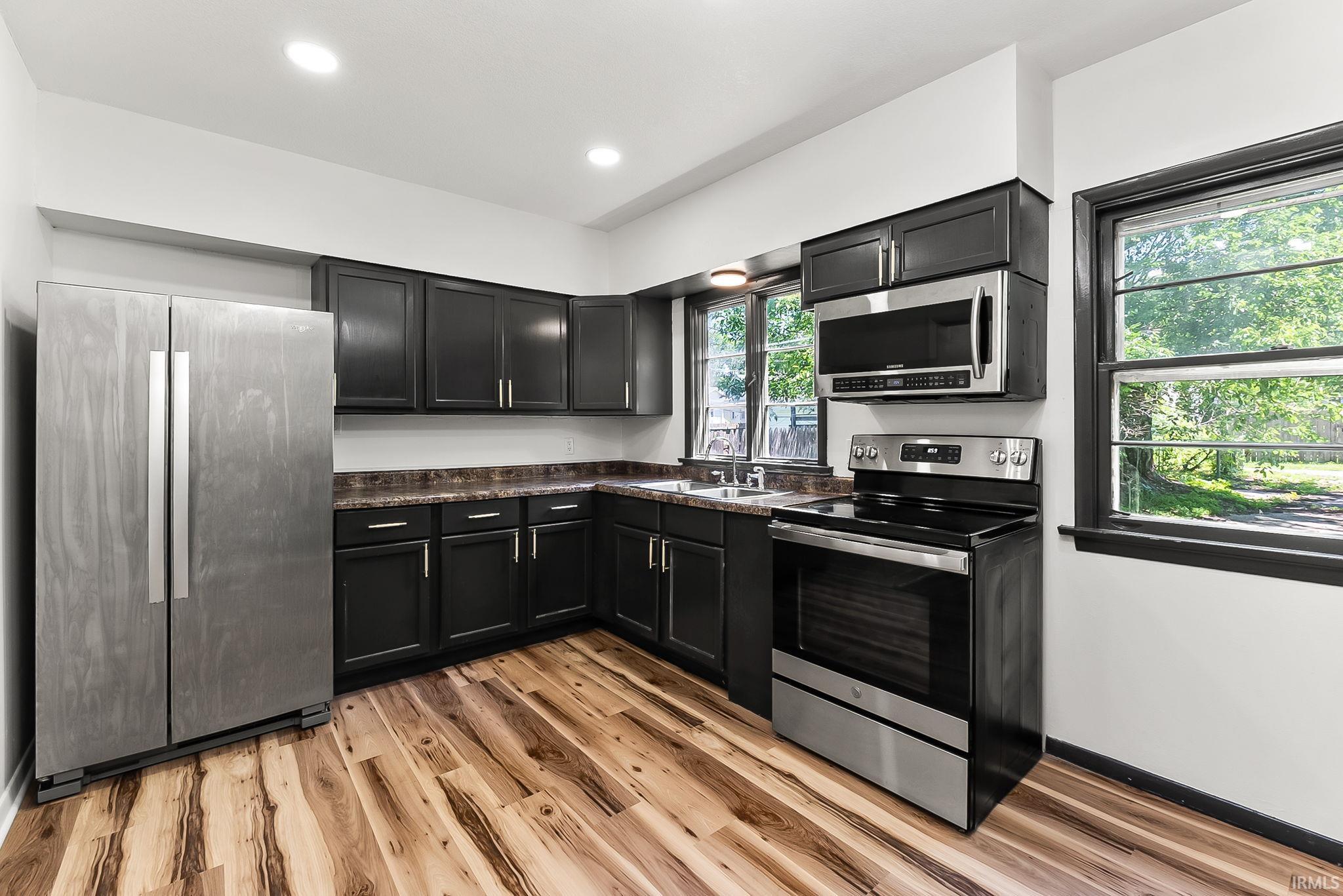 Kitchen featuring wood-finish flooring, dark cabinetry, and stainless steel appliances
