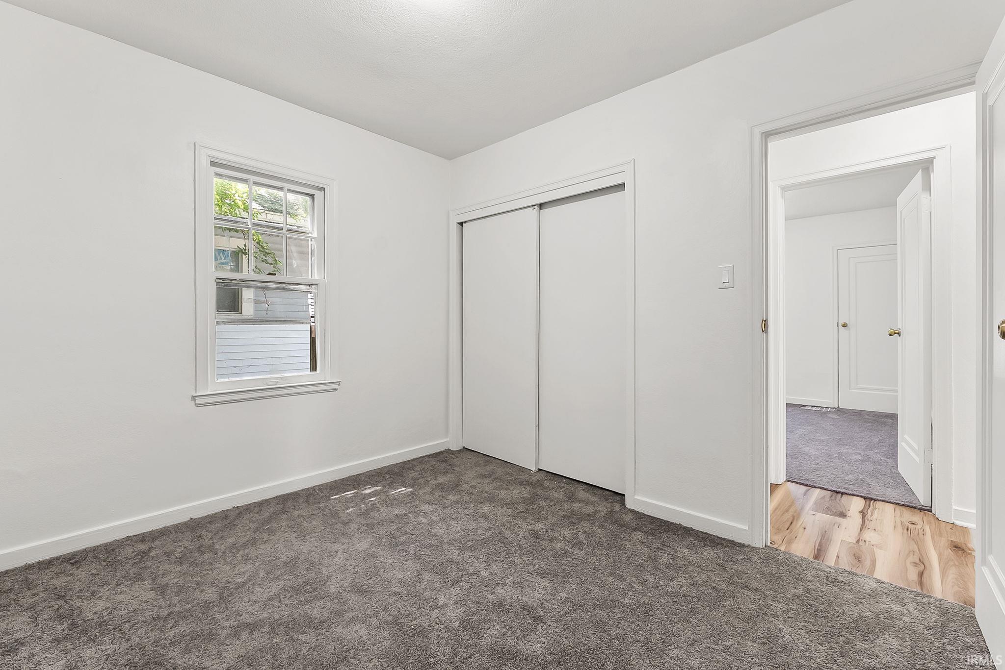 Bedroom featuring a double-hung window, plush grey carpeting, and a white sliding closet door