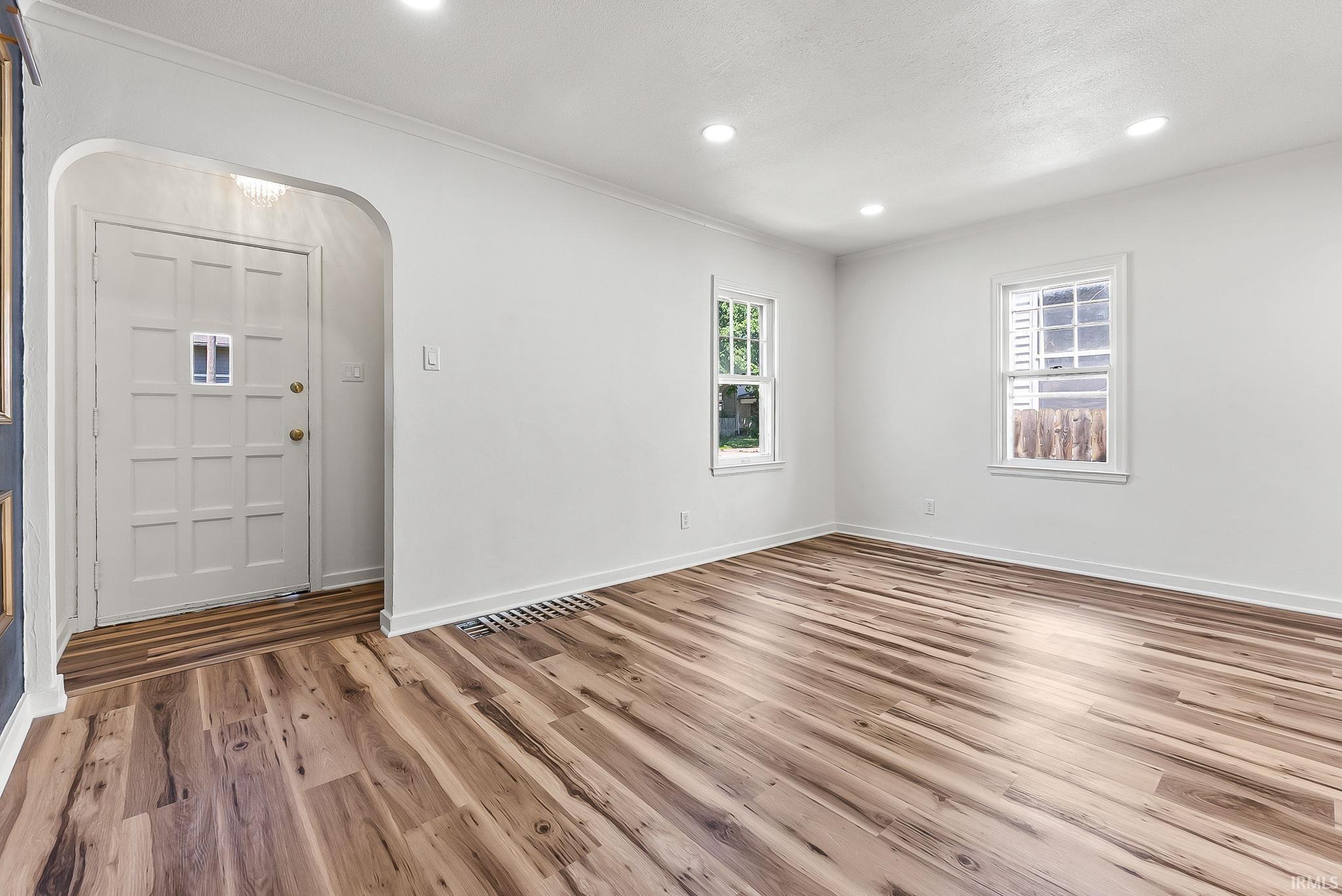 Open-concept living area with wood-finish flooring, white baseboards, and recessed lighting