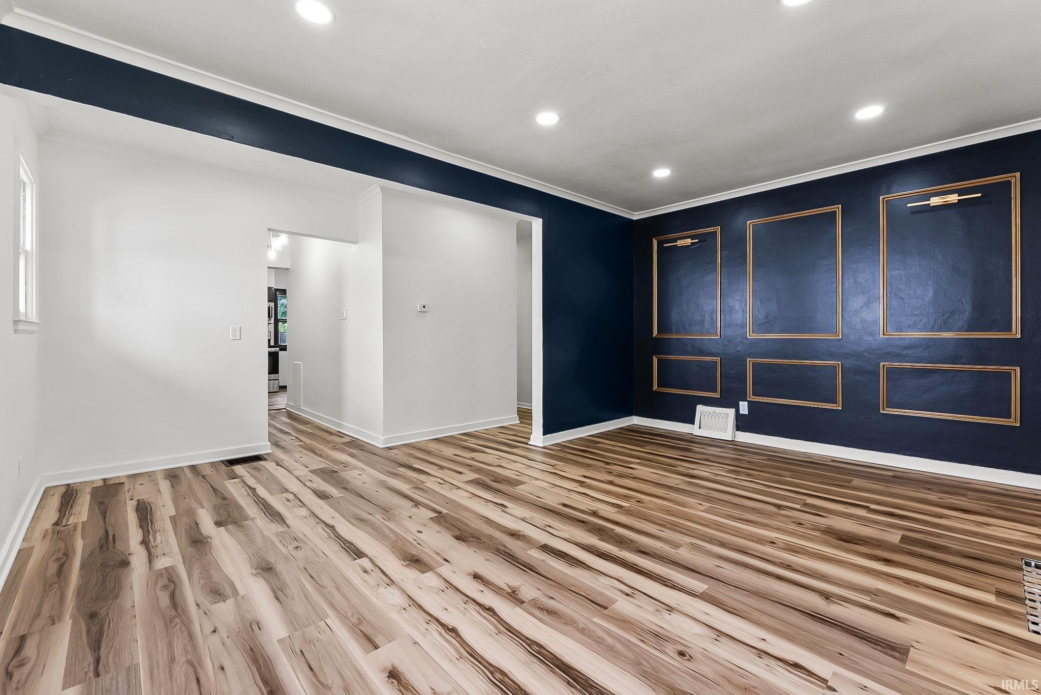 Spacious room featuring wood-finish flooring, recessed lighting, and crown molding