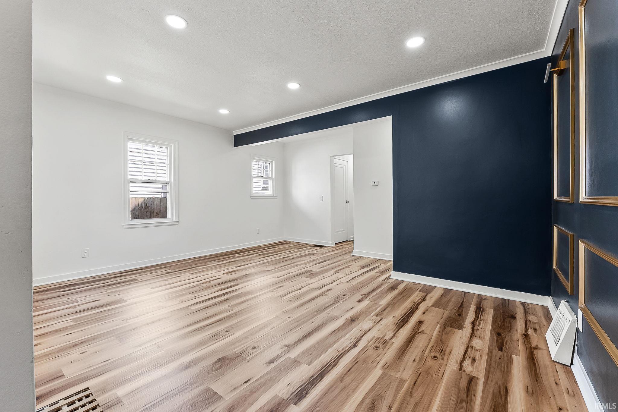 Bright interior space featuring wood-finish flooring, recessed lighting, and white walls complemented by a contrasting accent wall