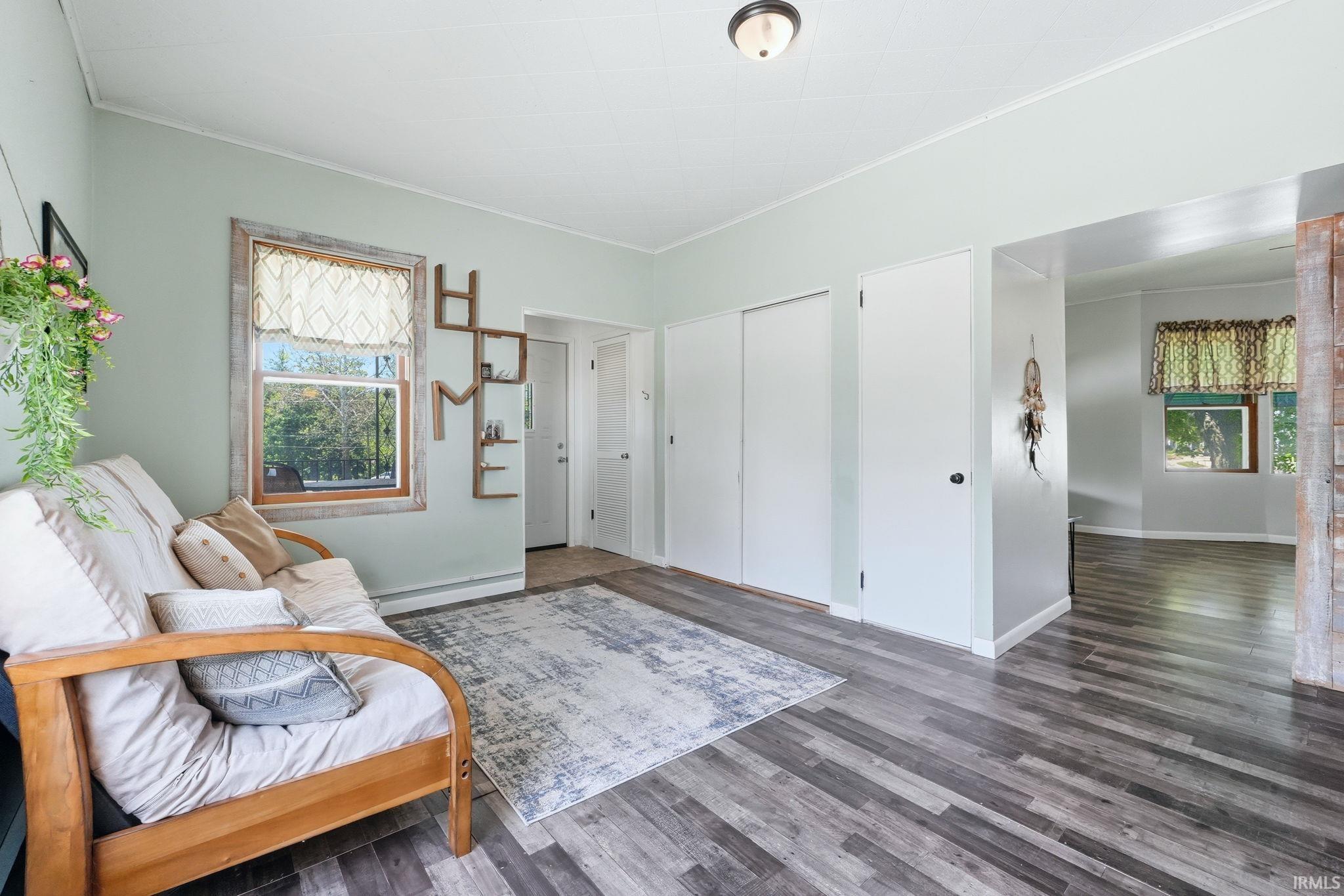 Interior room featuring wood-finish flooring, light-colored walls, and a window with wood trim