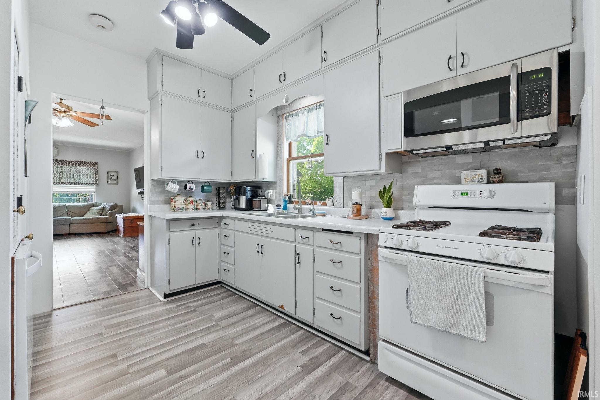 Kitchen featuring wood-finish flooring, white cabinetry, white countertops, and a tile backsplash