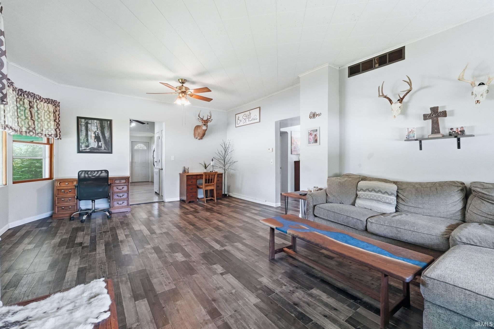 Spacious living area featuring wood-finish flooring, a ceiling fan, and light gray wall paint