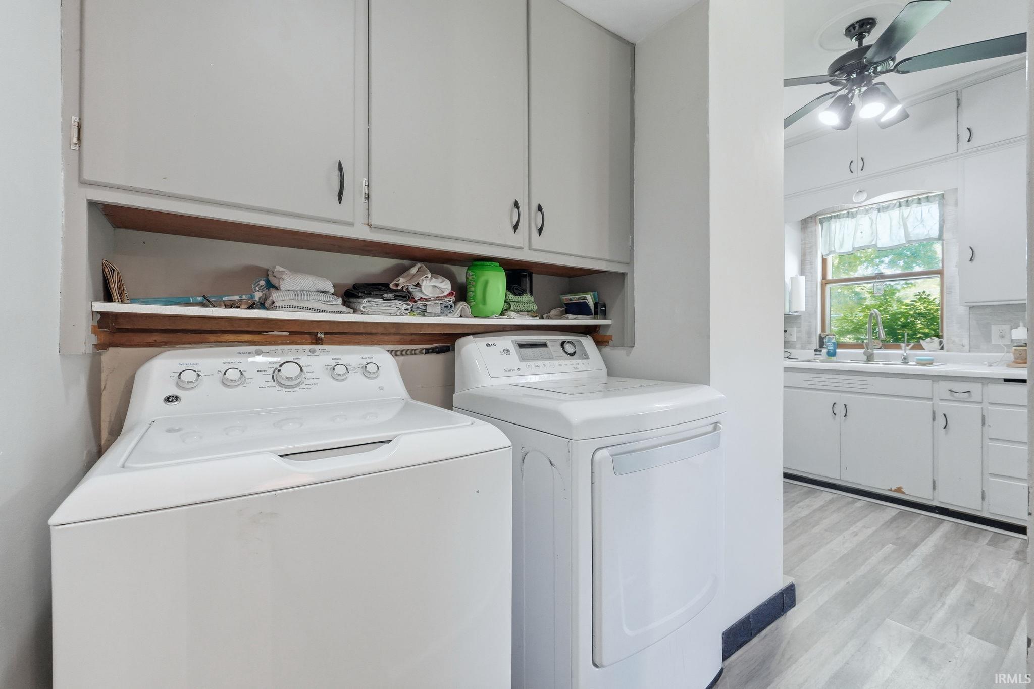 Dedicated laundry area featuring overhead cabinetry and open shelving