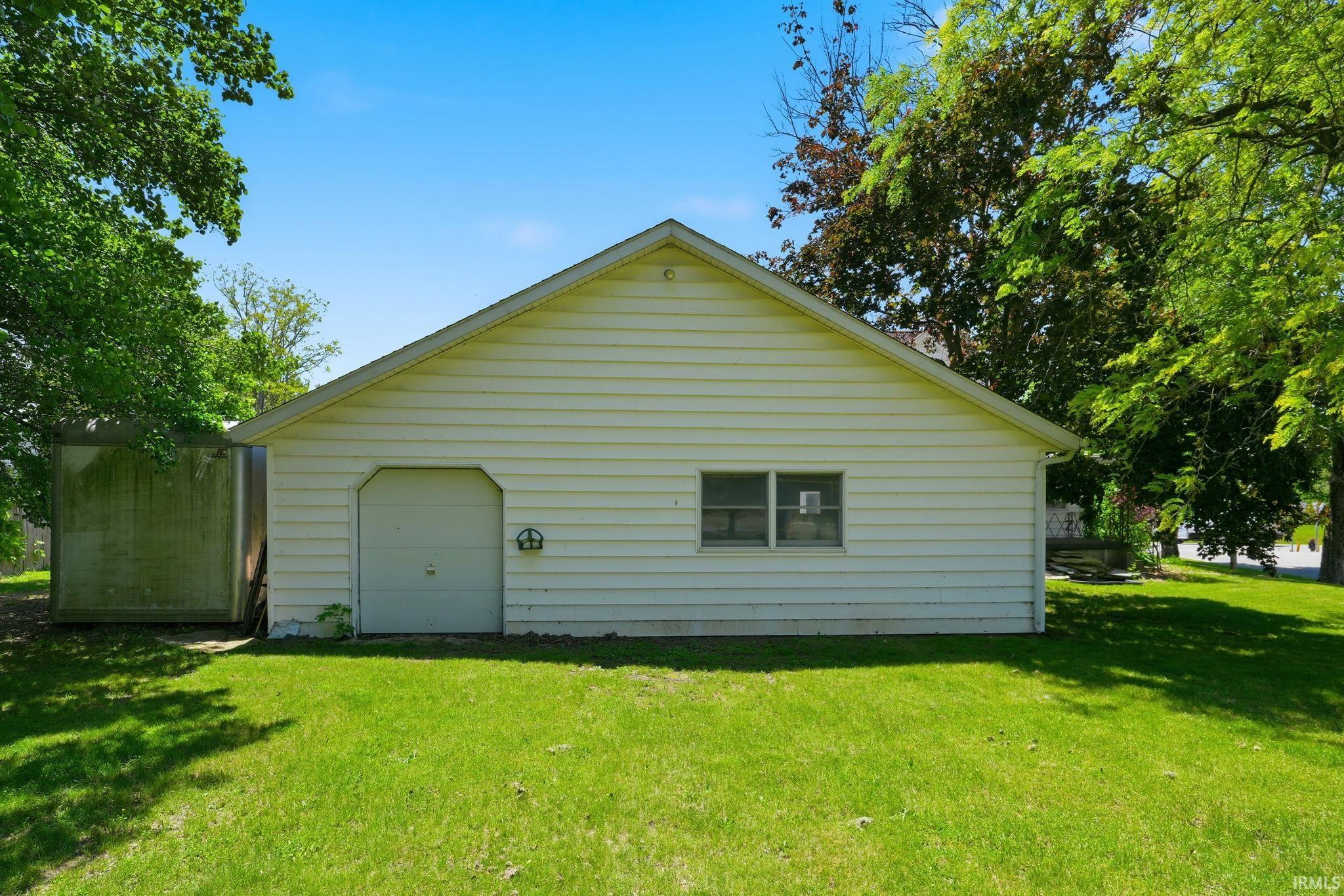 Detached auxiliary building with white siding and a peaked roof