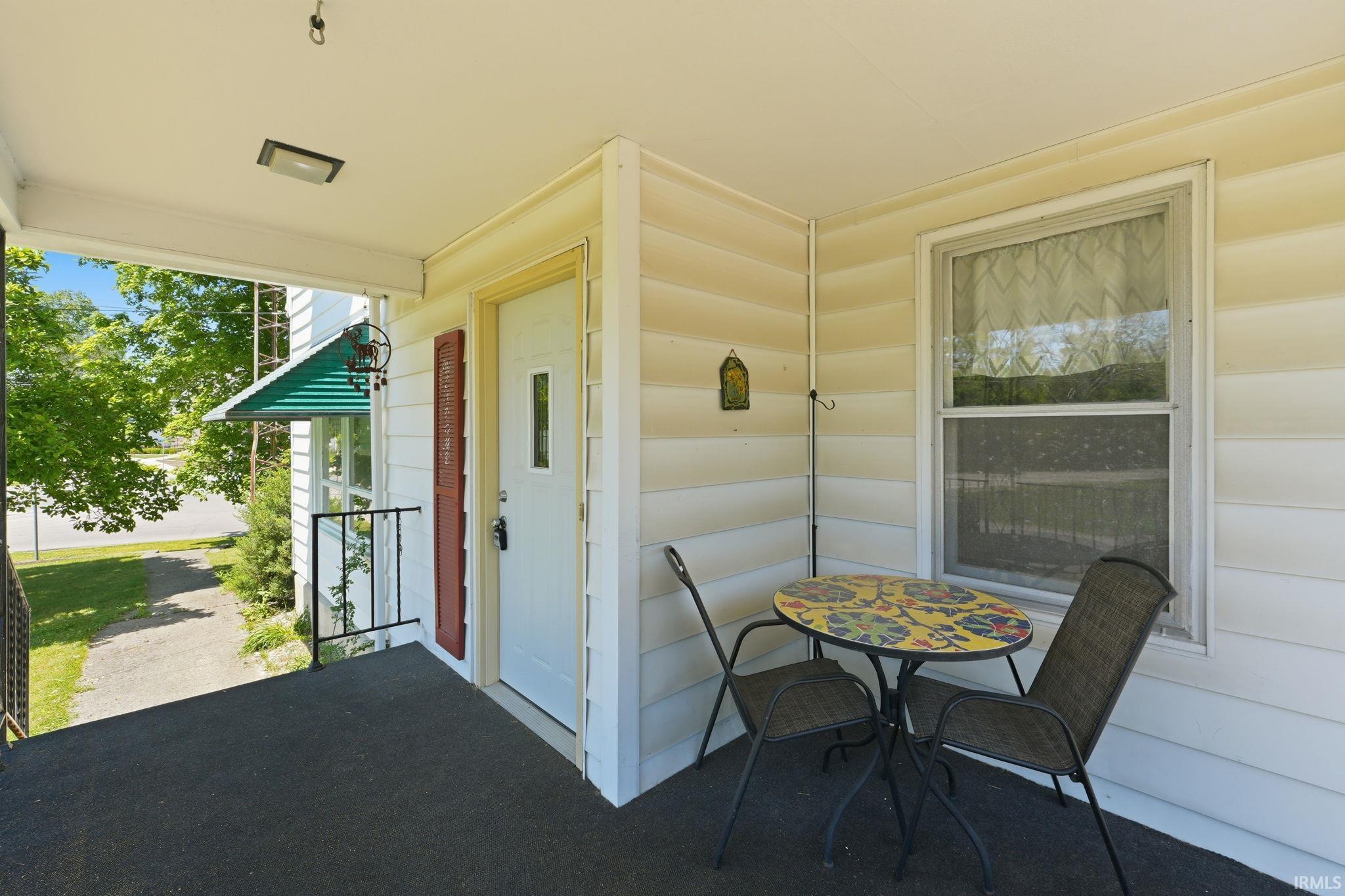 Covered front porch featuring a dark surface, white siding, and a white entry door with a privacy panel