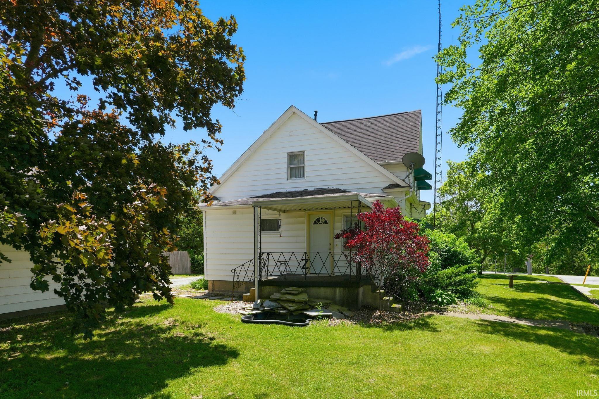 White siding residence featuring a covered front porch with decorative black metal railings