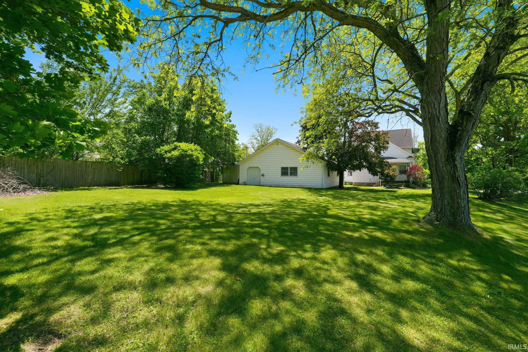 Expansive green lawn with mature trees providing dappled shade