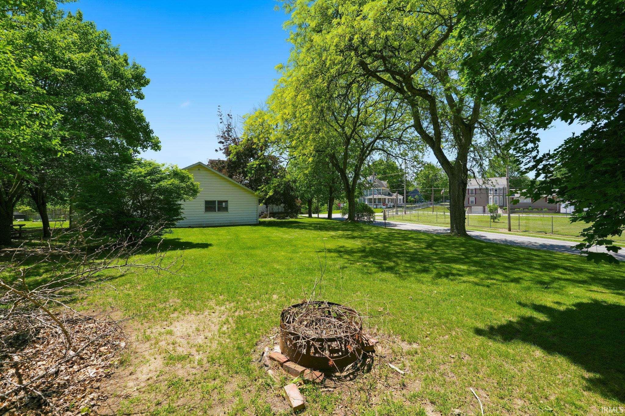 Expansive green lawn featuring mature trees providing ample shade