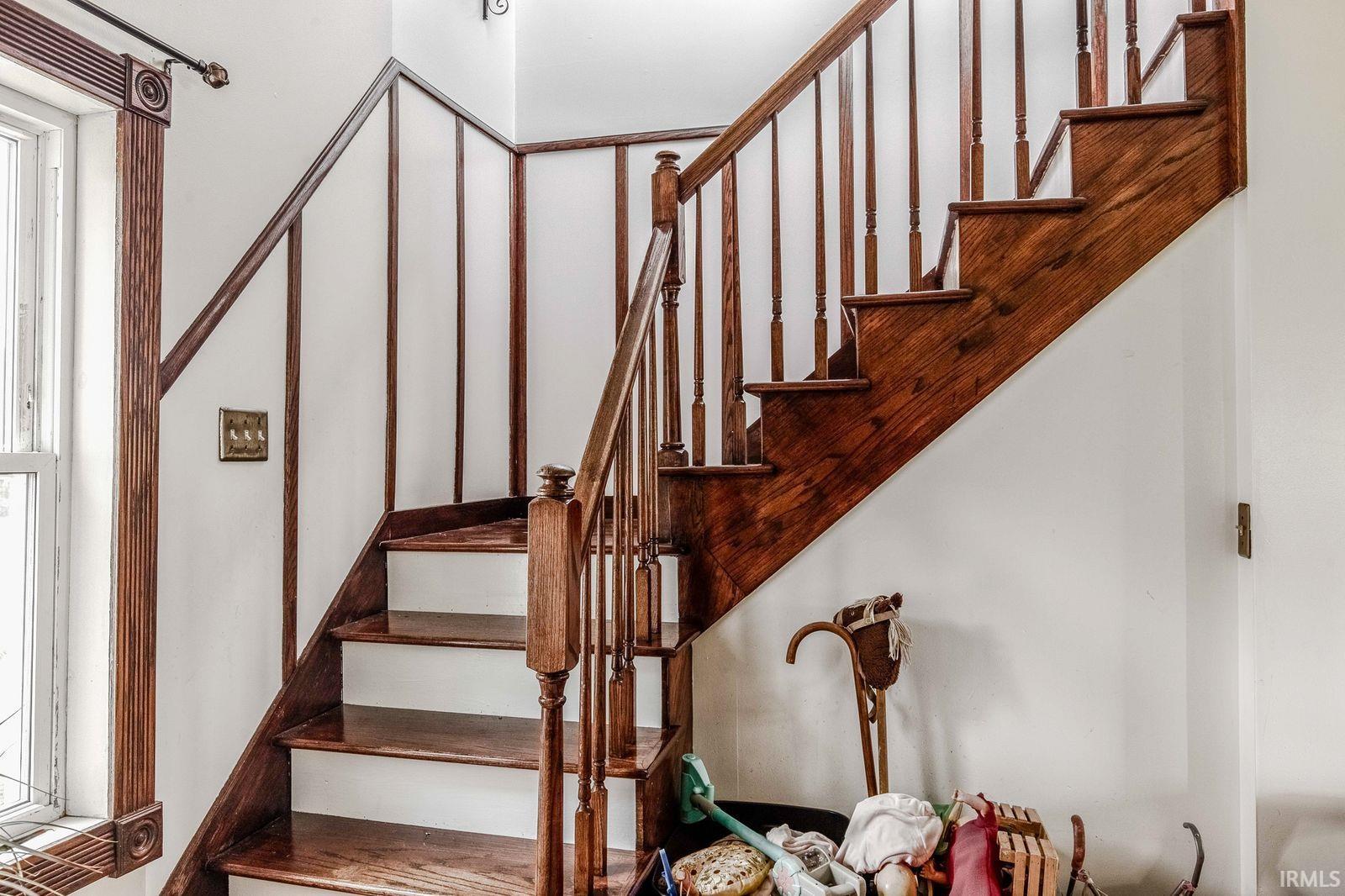 Hardwood staircase featuring a rich stain, turned balusters, and a matching handrail
