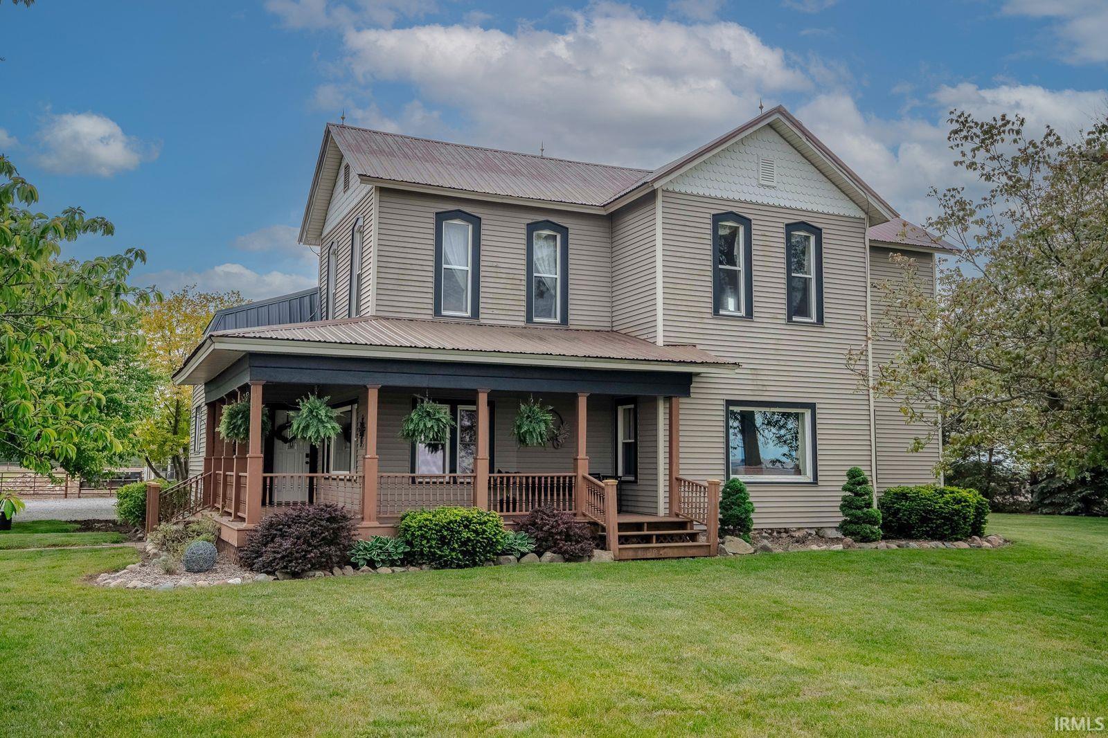 Two-story residence featuring light-colored siding and a covered porch with dark wood columns and railings