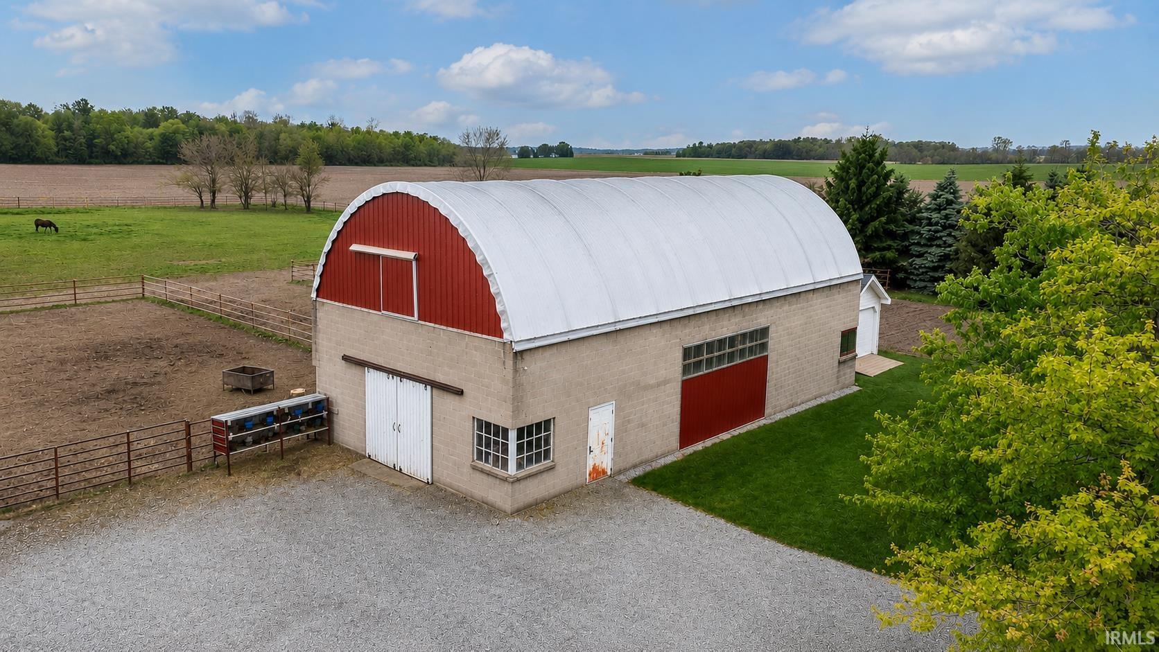 Freestanding barn structure featuring a quonset-style roof, red and beige exterior siding, and multiple entry points