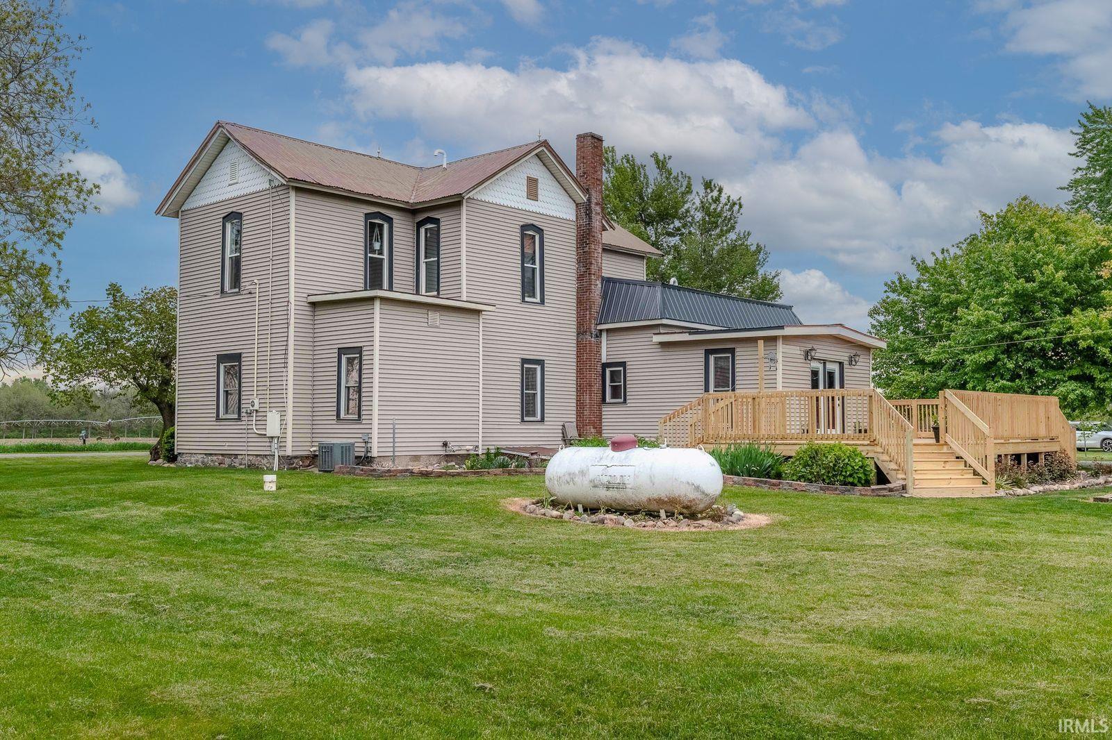 Rear exterior featuring a multi-level wooden deck with railings, a metal roof addition, and a prominent chimney