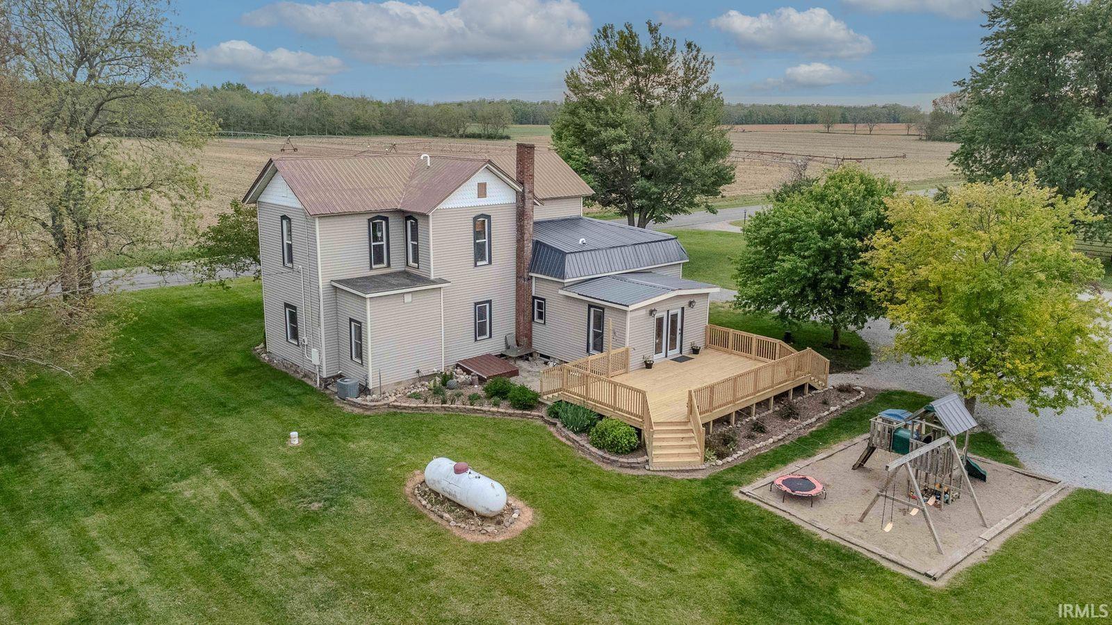 Expansive backyard featuring a large wood-finish deck with railings, manicured lawn, and mature trees