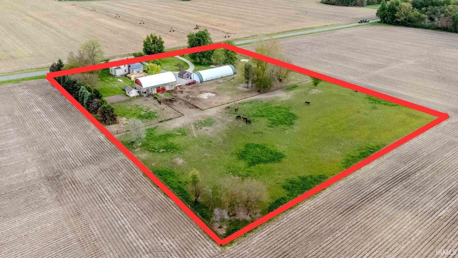 Expansive agricultural property featuring multiple structures including a main residence, barn, and hoop house