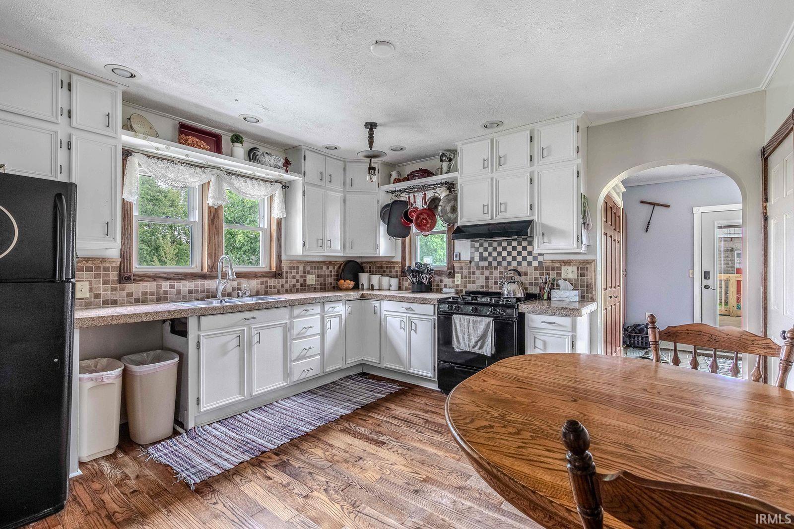 U-shaped kitchen featuring white cabinetry, a tiled backsplash, and wood-finish flooring