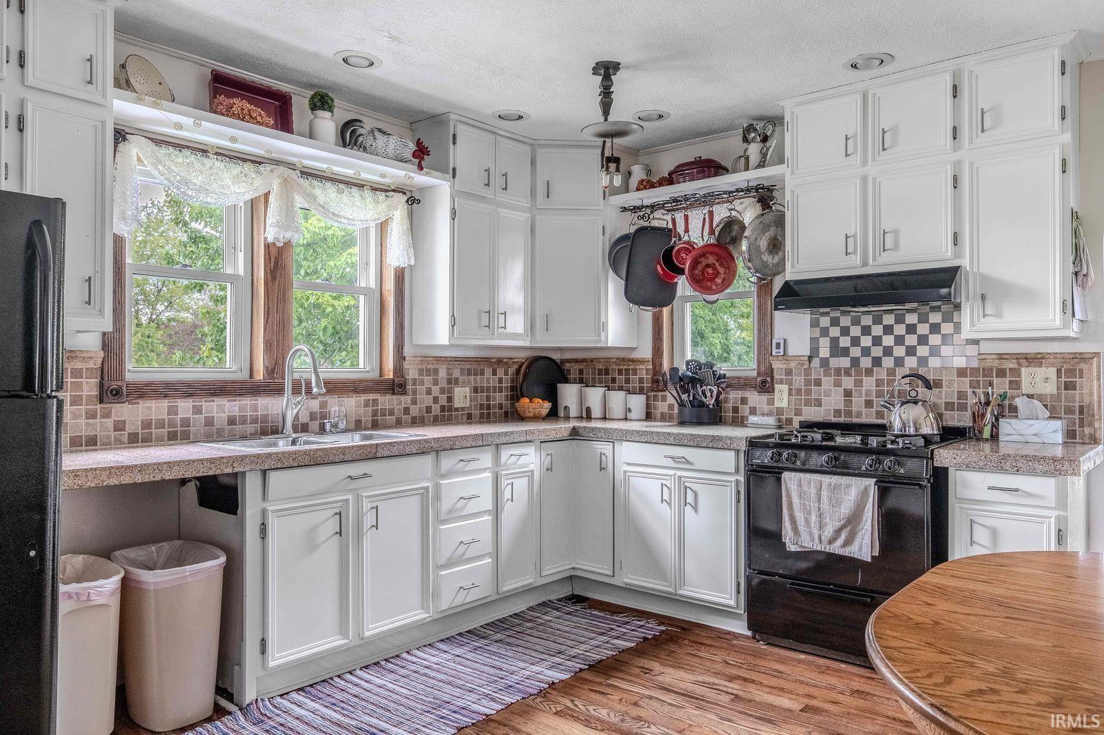 Functional kitchen featuring white cabinetry, light countertops, and wood-finish flooring