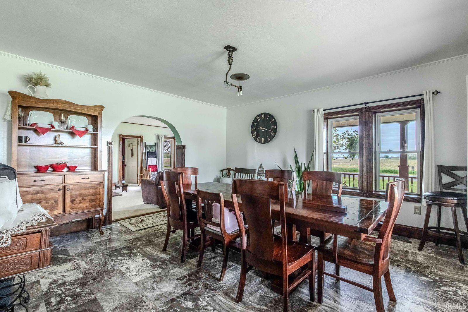 Spacious dining area featuring patterned flooring, an arched entryway, and a window with a rural landscape