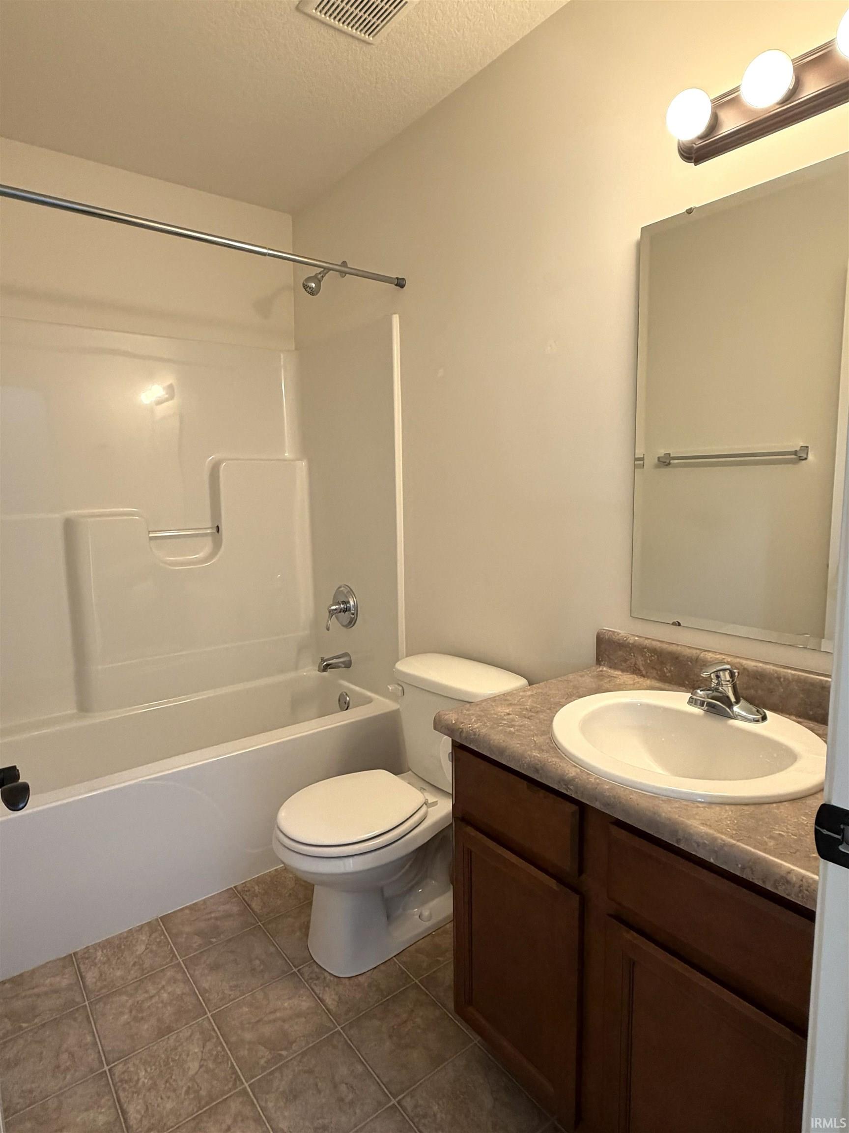 Full bathroom featuring a tub/shower combination with chrome fixtures, a complete vanity with an integrated sink, dark wood-finish cabinetry, and a textured countertop