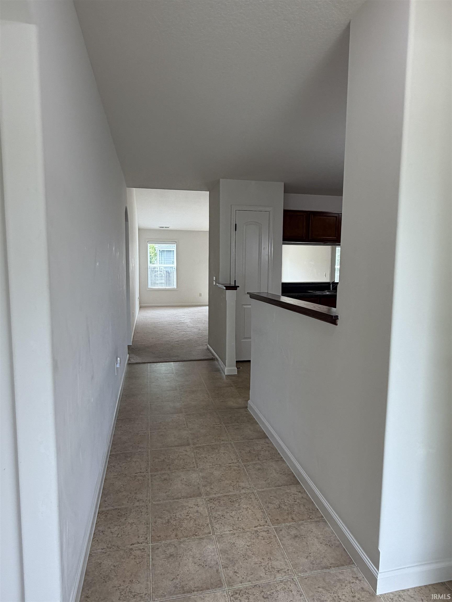 Entryway featuring square tile flooring, white baseboards, and a half-wall with a dark wood cap